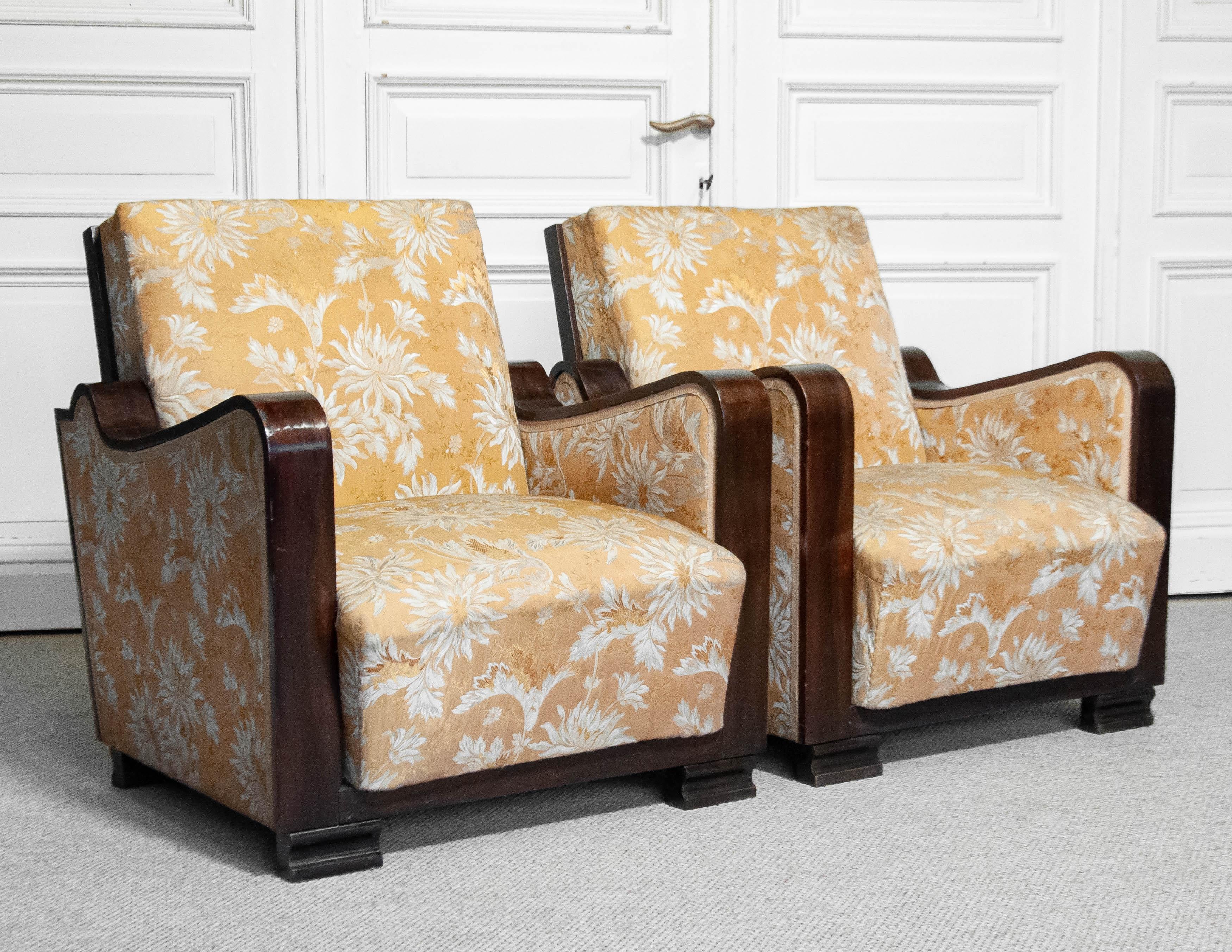 A stunning pair of Swedish Art Deco armchairs from the 1920s, featuring its original golden jacquard fabric with an elegant floral pattern. The fabric shows some wear consistent with age and use like little fading and little holes. The chairs have a