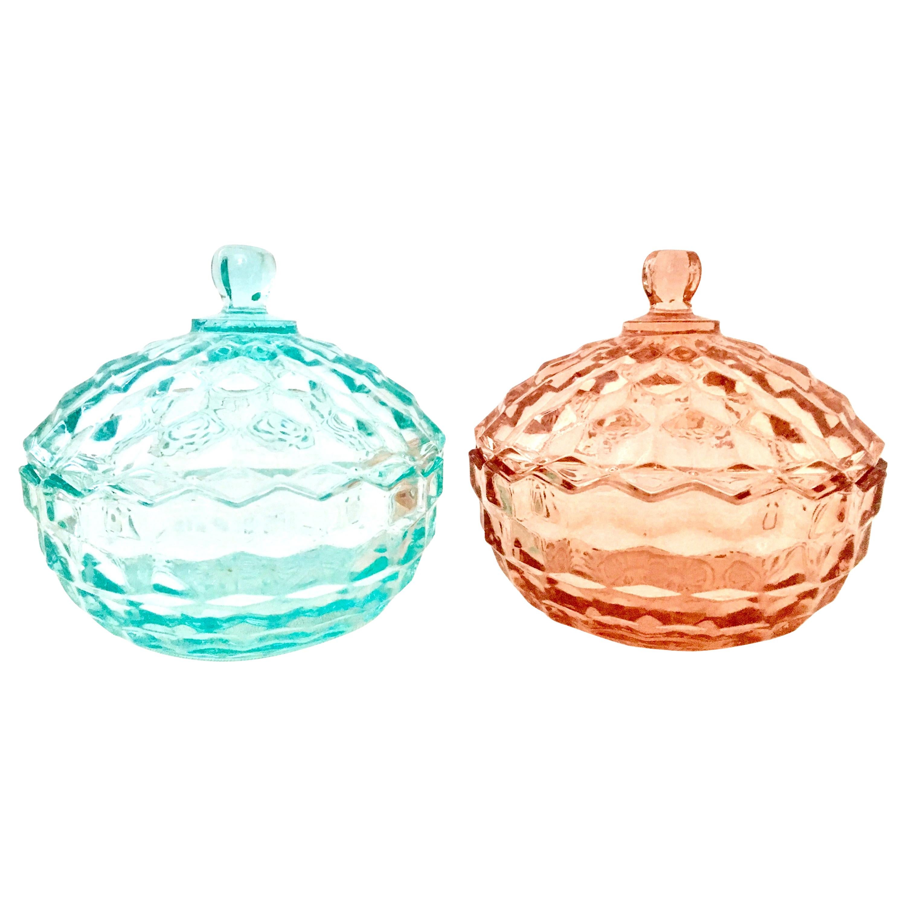 1920s American diamond cut depression era glass lidded jars, set of two. Set includes one teal blue and one pink lidded jar.
