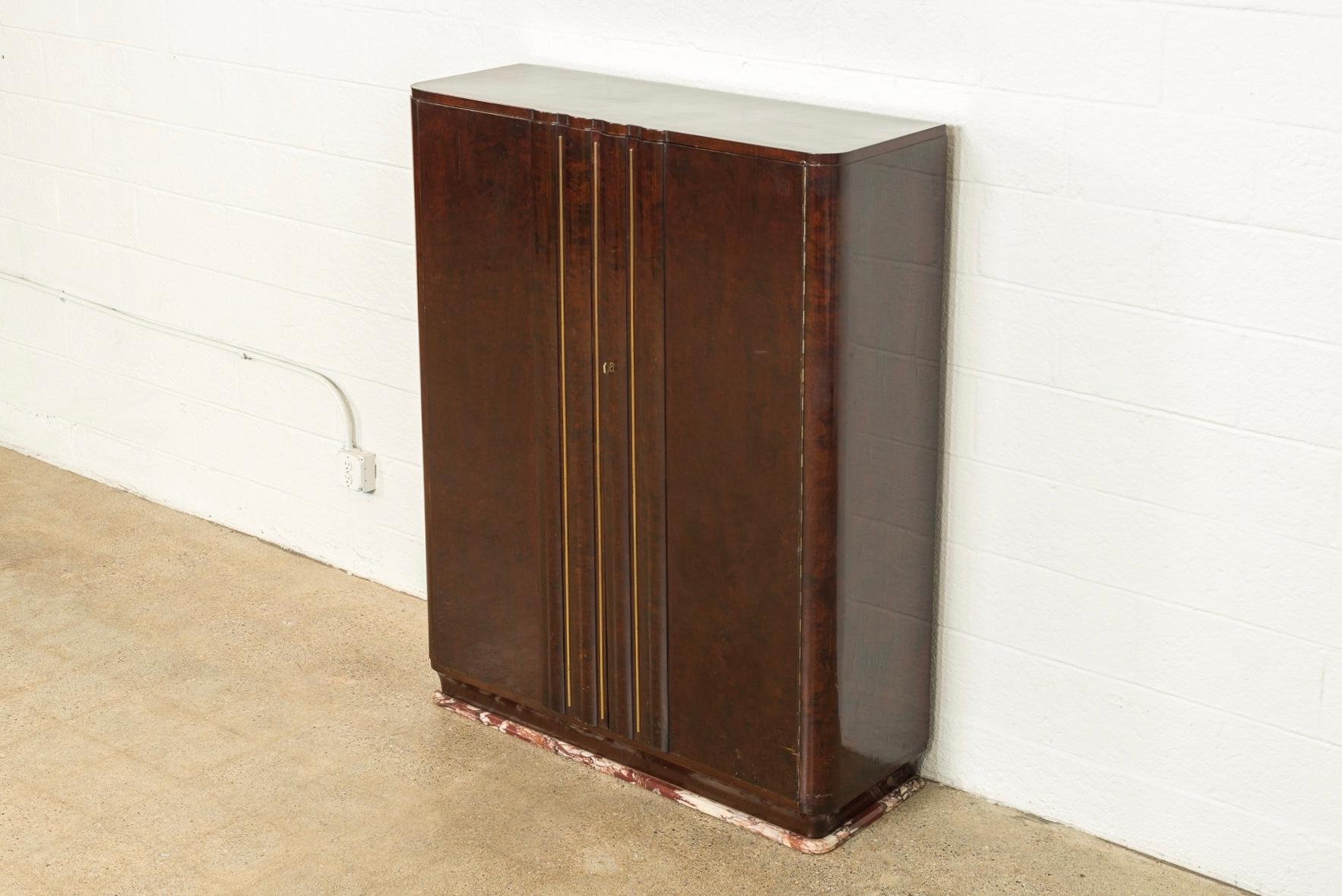 This exceptional Art Deco burl wood bronze decorated two door bar cabinet is circa 1920. Exquisitely crafted, the lacquered burlwood cabinet features two fluted front doors with vertical bronze stripe decoration. The cabinet rests on a rouge marble