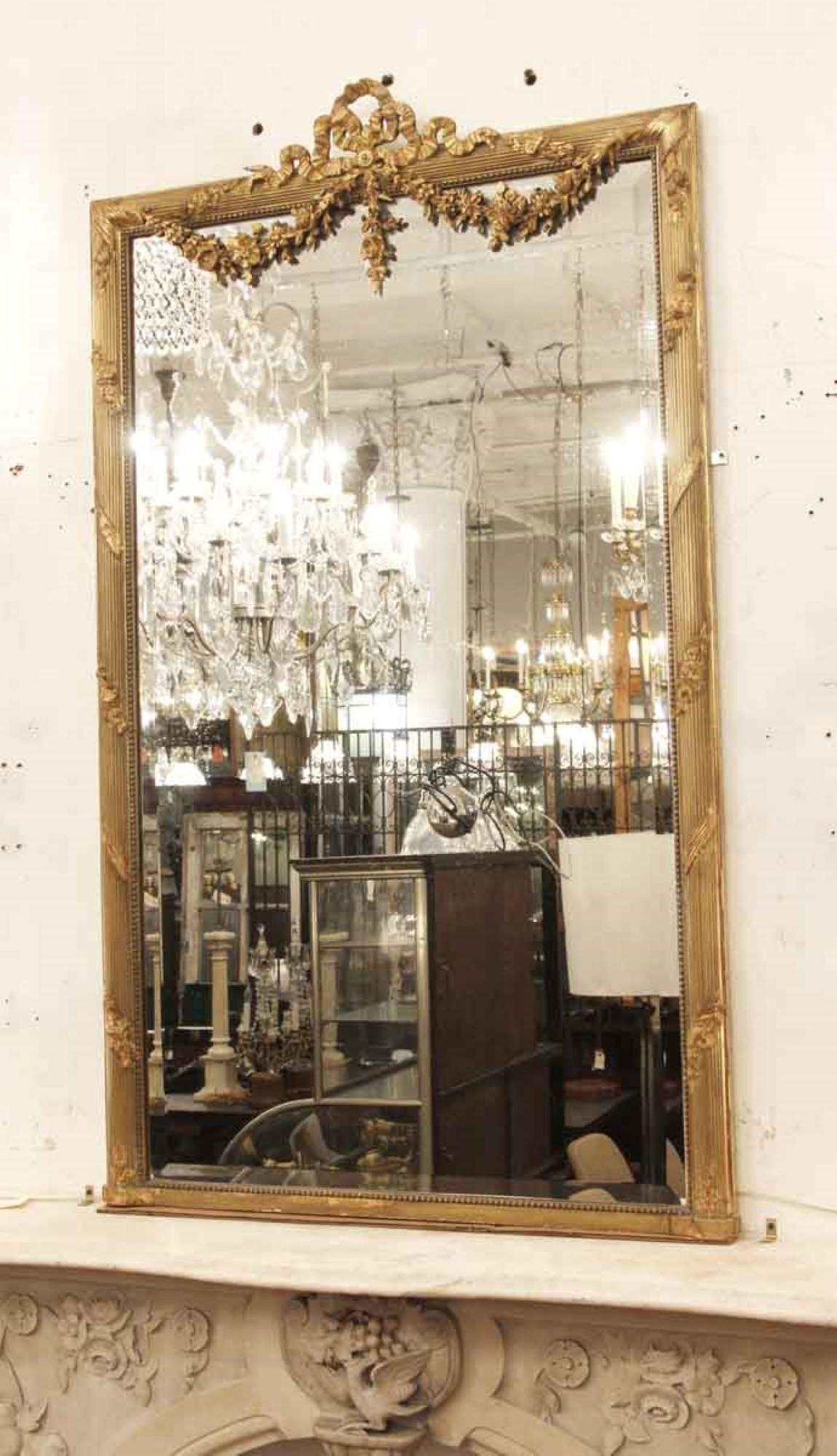 1920s decorative mirror gold gilded with ribbons and floral details. This can be seen at our 333 West 52nd St location in the Theater District West of Manhattan.