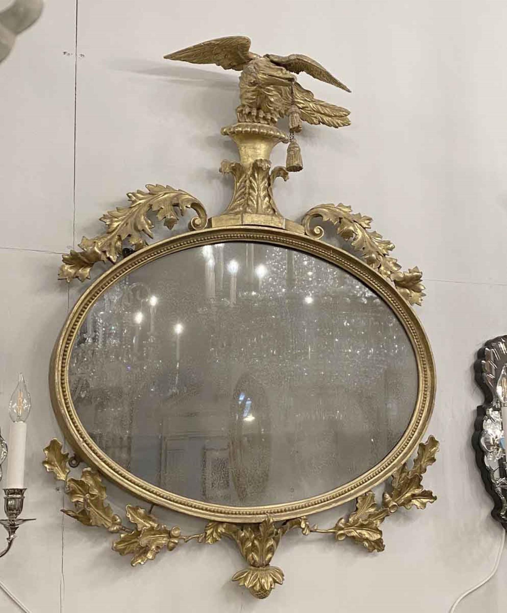 1920s hard carved gold gilt mirror with a carved wood eagle holding tassels with his beak. Original distressed mirror set into a beaded wood frame. Maple leaves and acorns completes the setting. Retrieved from a luxury apartment on East 61st St in