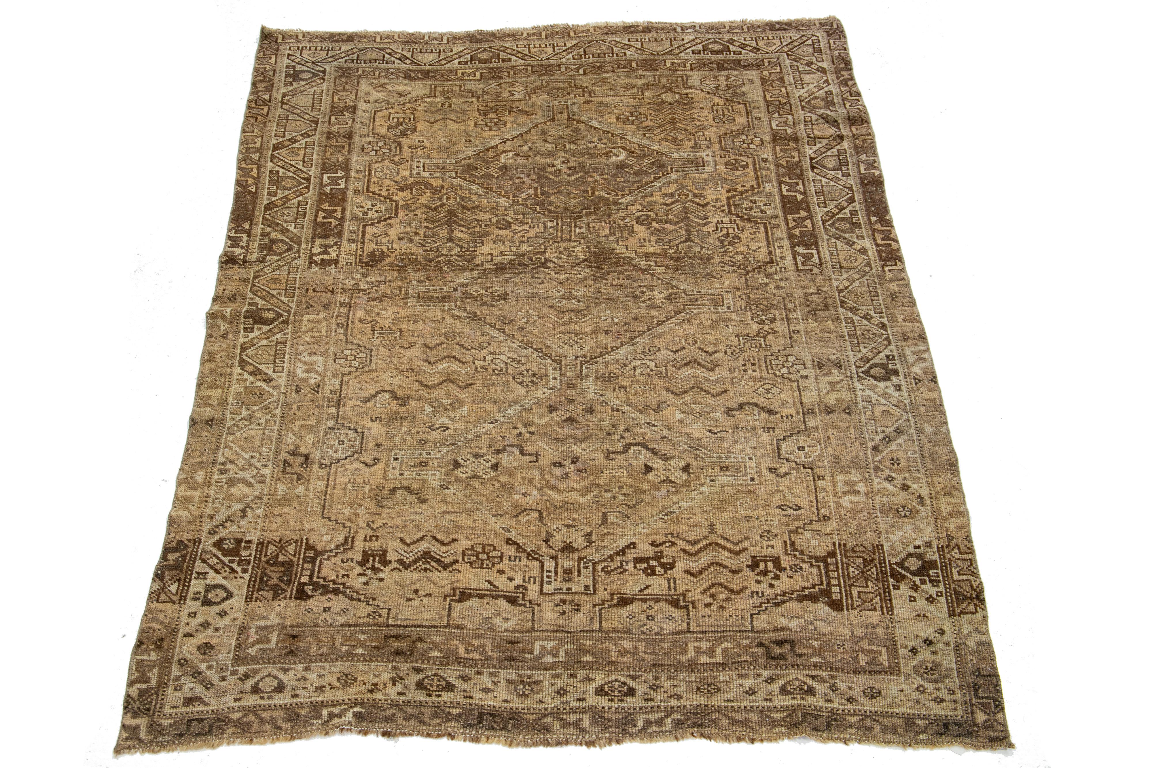 This Persian Shiraz wool rug showcases an exquisite traditional floral medallion design with striking beige and pink accents against a tan background. 

This rug measures 4'8