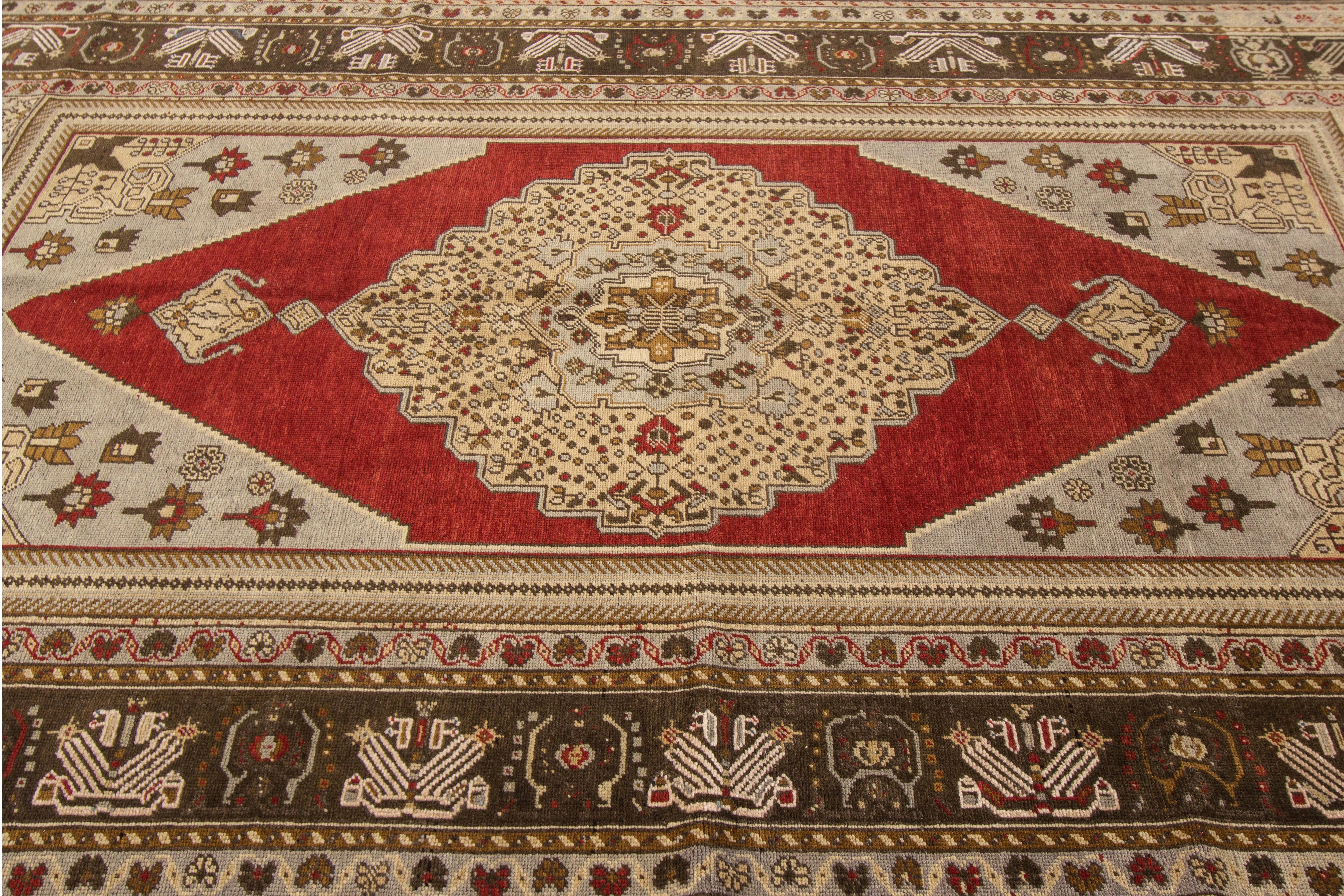 A hand knotted 1920s antique Khotan rug with a red and beige medallion design. This rug measures 6' x 9'2