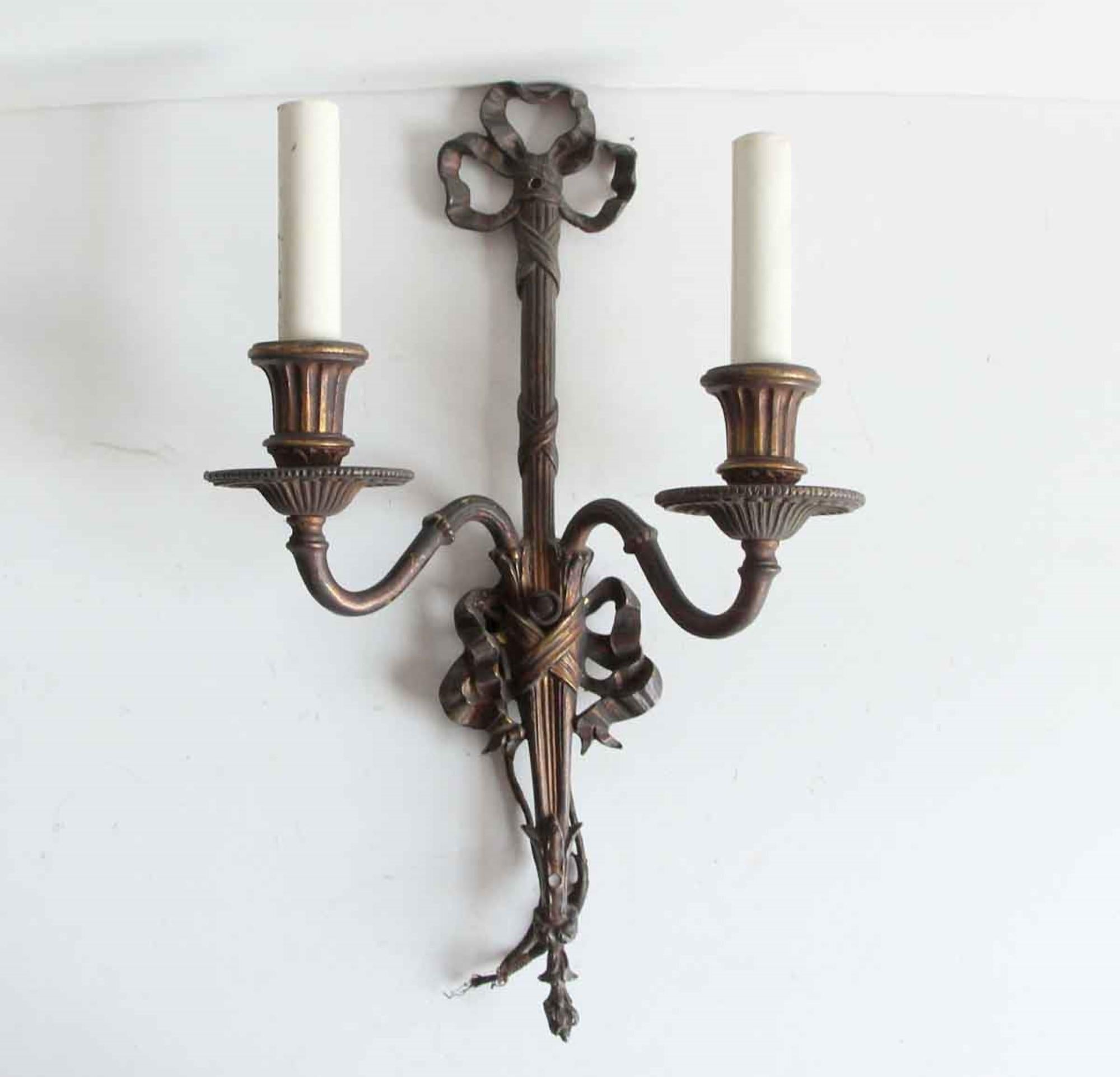 1920s pair of solid bronze tied ribbon two arm sconces with decorative stems and arms. Priced as a pair. Price includes restoration. This can be seen at our 400 Gilligan St location in Scranton. PA.