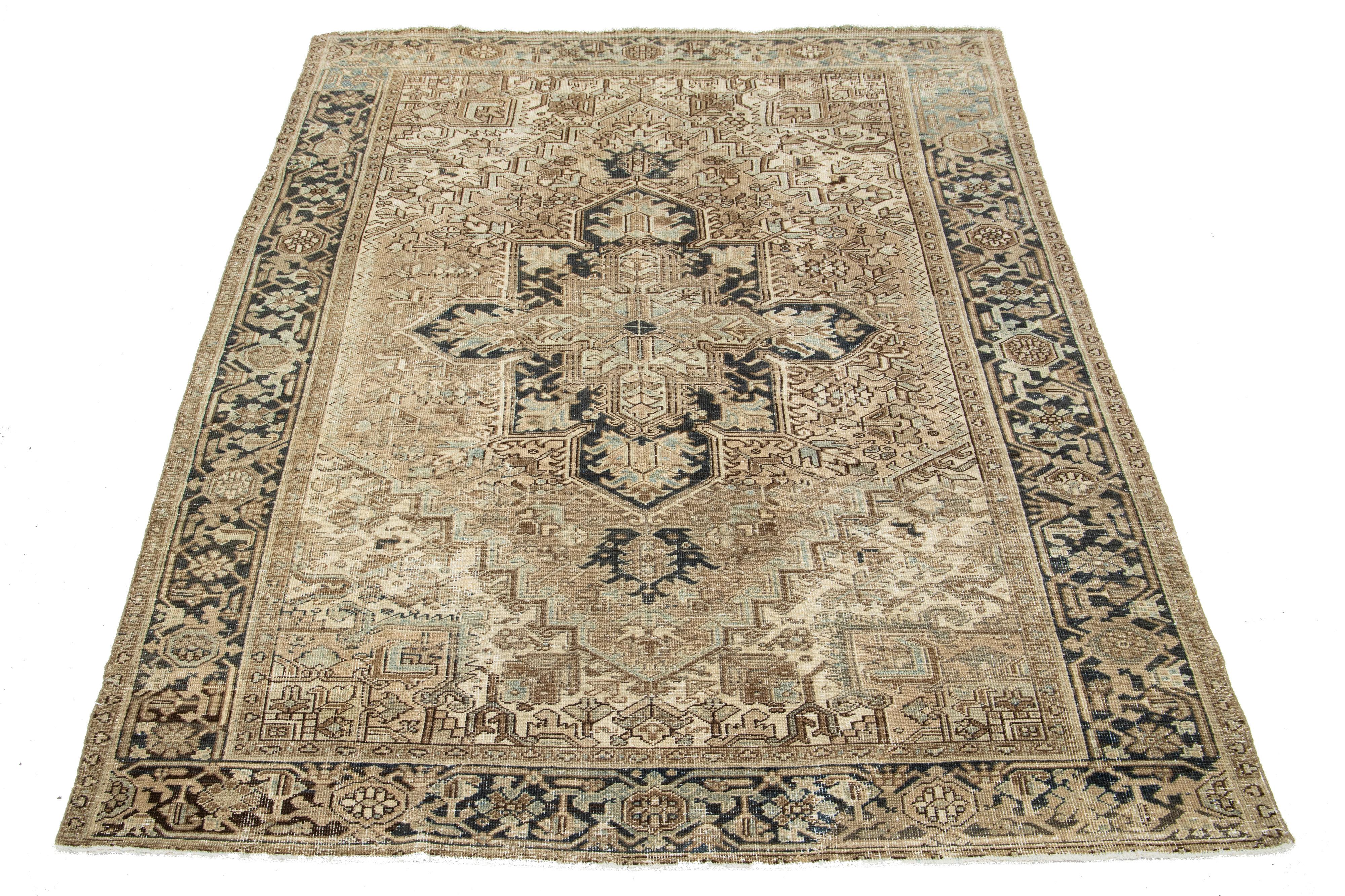 Ce tapis persan ancien en laine Heriz présente un remarquable motif de médaillon bleu qui anime un luxueux fond beige foncé.

Ce tapis mesure 6'8'' x 9'4
