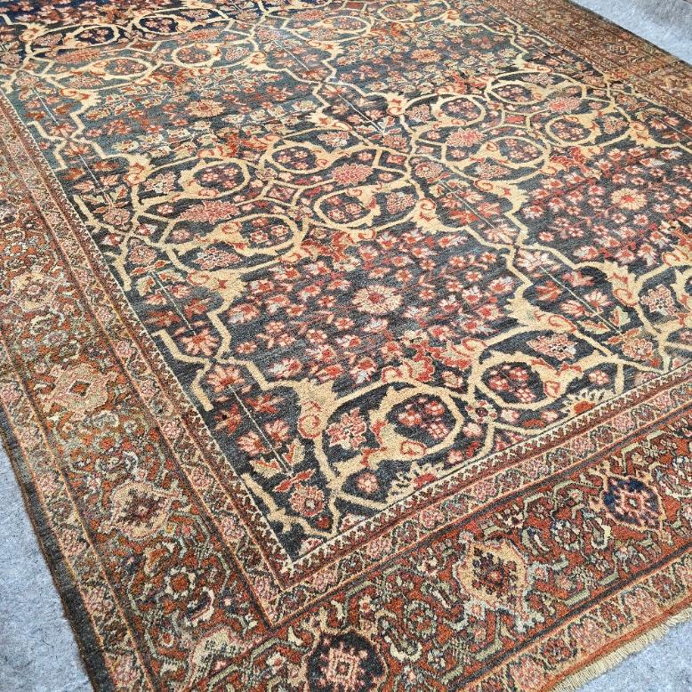 Faites entrer chez vous l'élégance de l'artisanat persan avec cet exquis tapis antique Persian Mahal, une pièce authentique du début du 20e siècle. Mesurant 10,5 x 13,5 pieds, ce tapis en laine noué à la main présente un gracieux motif floral sur
