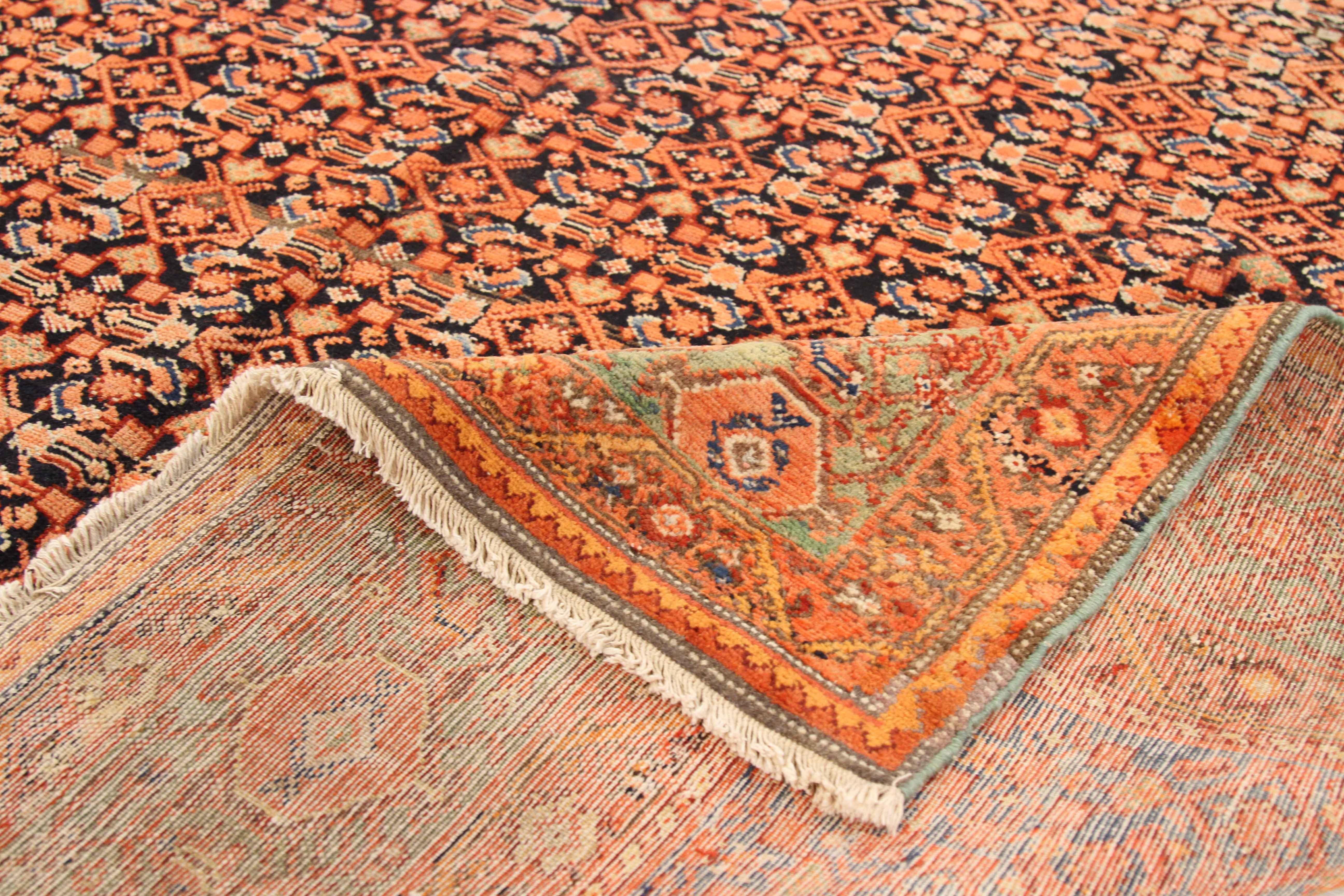 Antique Persian rug made from handspun fine wool and organic vegetable dyes. It features a bold rust and black ensemble of geometric and nature-inspired patterns that make it a great centerpiece in a contemporary and modern space. It has a dimension