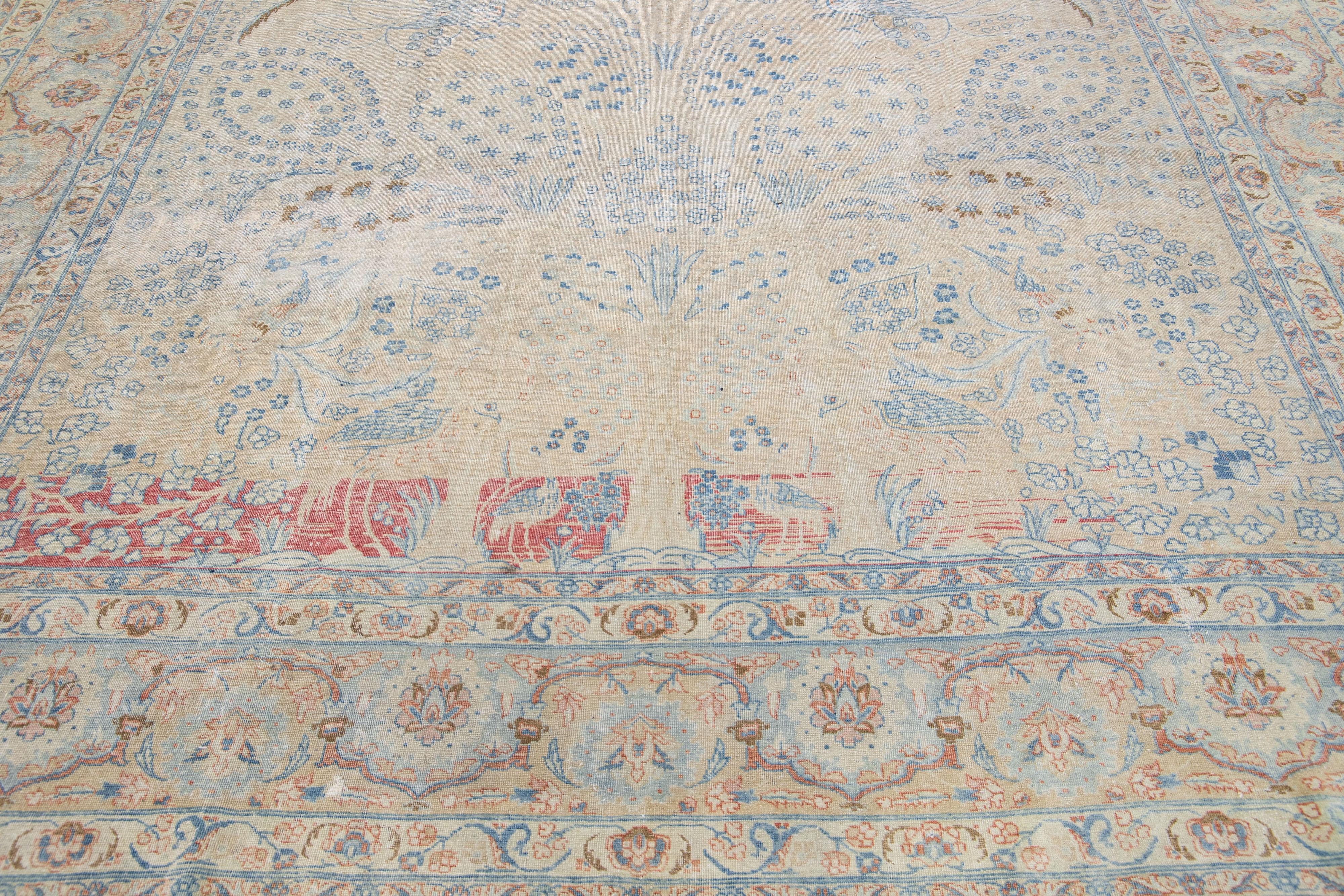Beautiful antique Persian hand-knotted wool rug with a beige color field. This piece has a blue-designed frame with peach and brown accents in a gorgeous all-over floral design.

This rug measures: 9'8