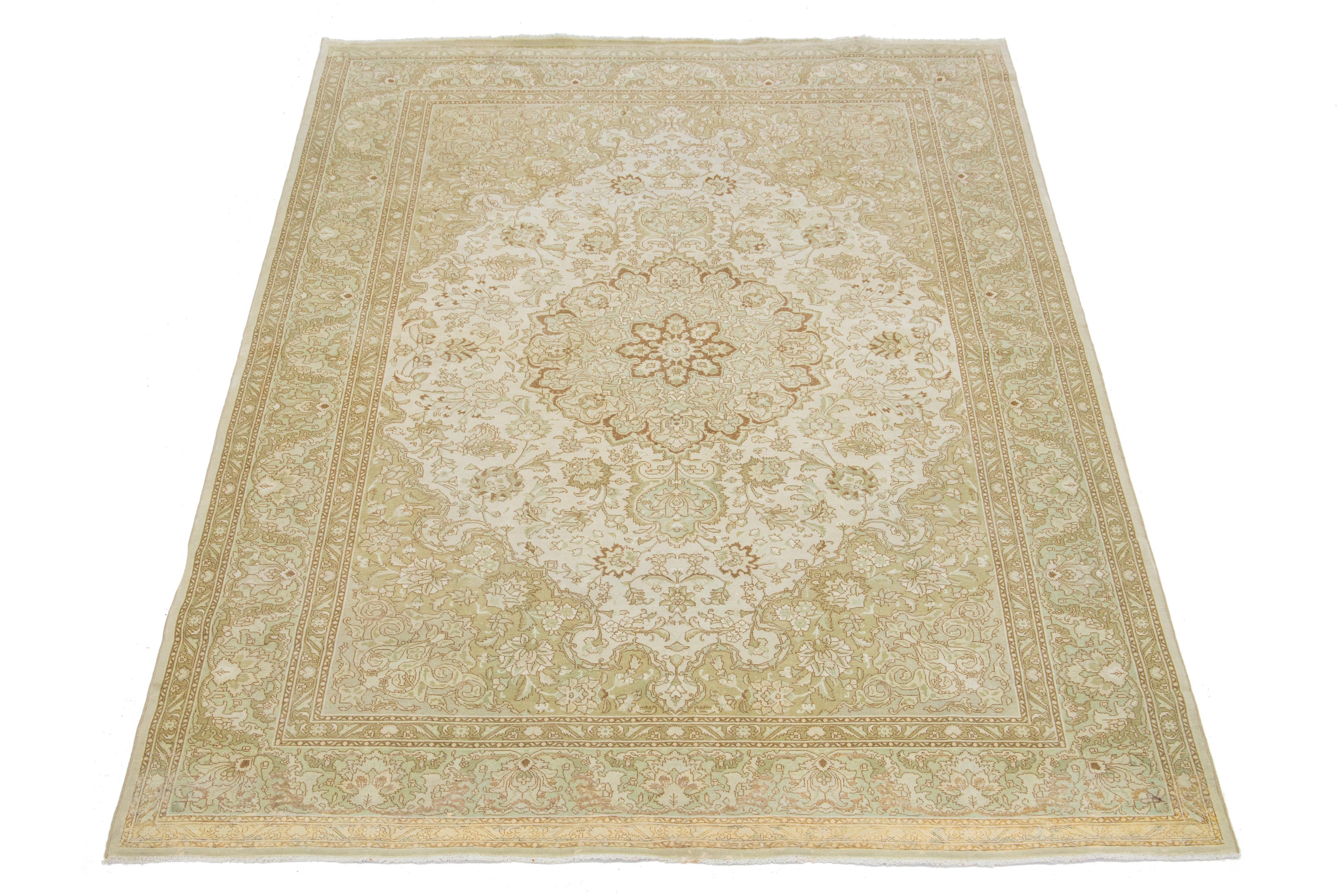 1920s Persian Tabriz wool rug, handcrafted, showcases a traditional floral pattern. The contrast between the beige backdrop and the bold blue and brown emphasizes the design.

This rug measures 6'9