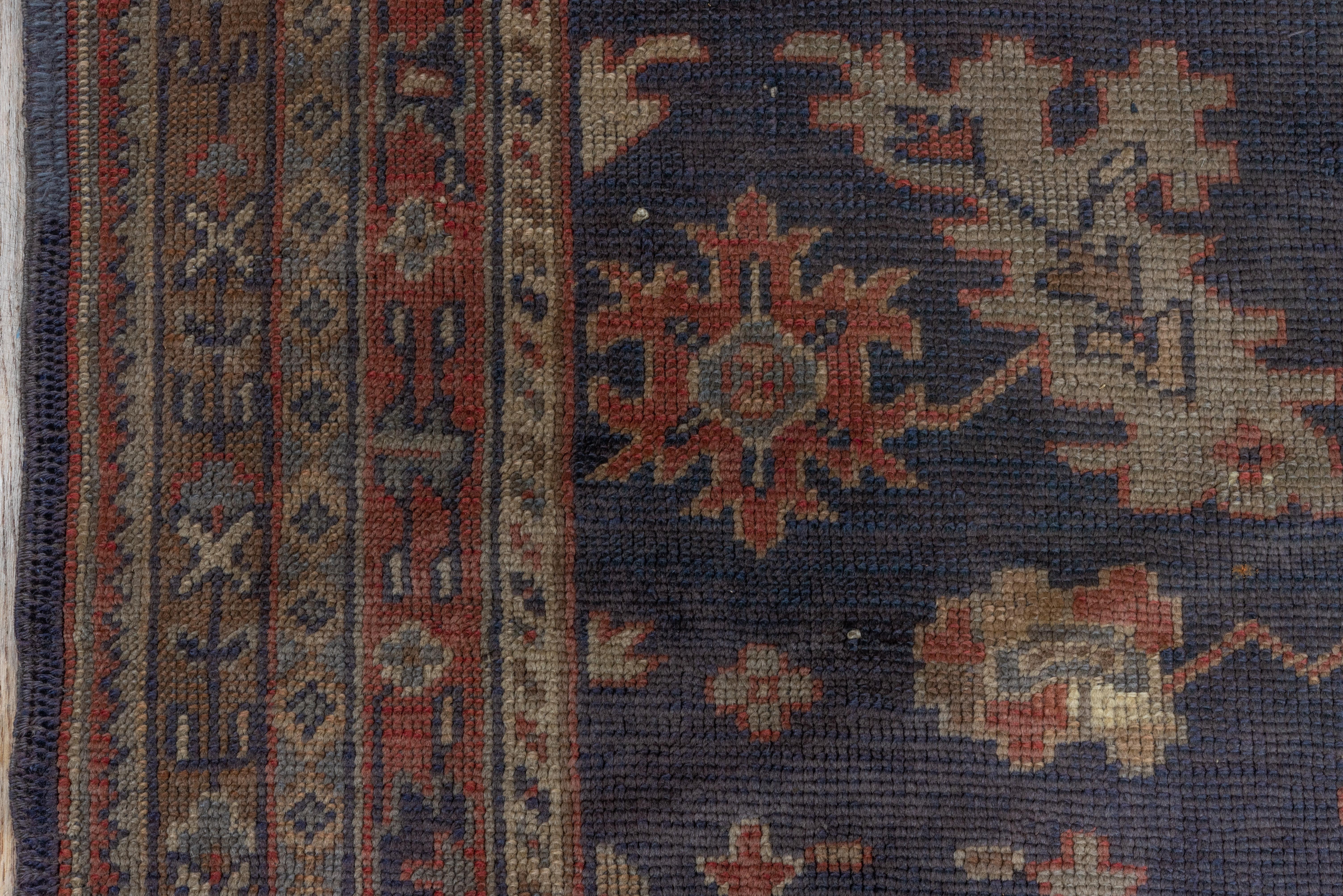 An attractive west Anatolian long rug with an abrashed navy ground decorated with ragged palmettes and slanted acanthus leaves in nine full rows, ecru, red, pale blue and green accents. Narrow red main border with leaves and hexagons.