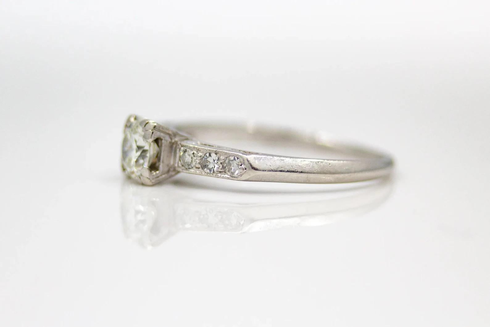 A classic late Art Deco period diamond engagement ring in platinum. Centered by a 0.53 carat Old European Cut diamond grading as H color and VS2 clarity. Framing the center diamond are six accenting diamonds weighing 0.09ctw.

In excellent condition