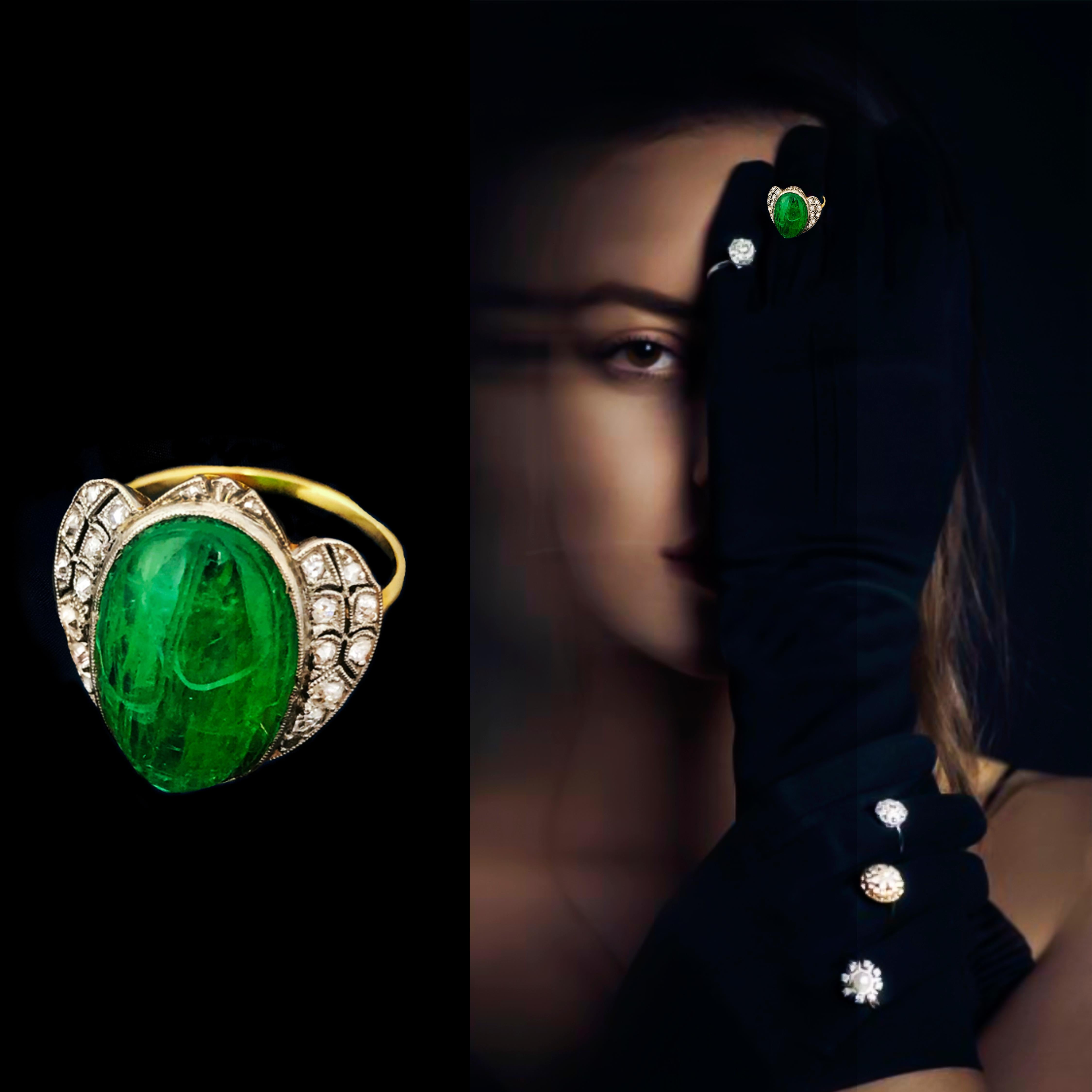 The present 18kt yellow and white gold ring is a very exquisite Art Deco Egyptian Revival 10 carat Hand Carved Emerald Scarab Cabochon ring accented by round cut diamonds and set into a delicately made open milegrain setting. The ring is attributed