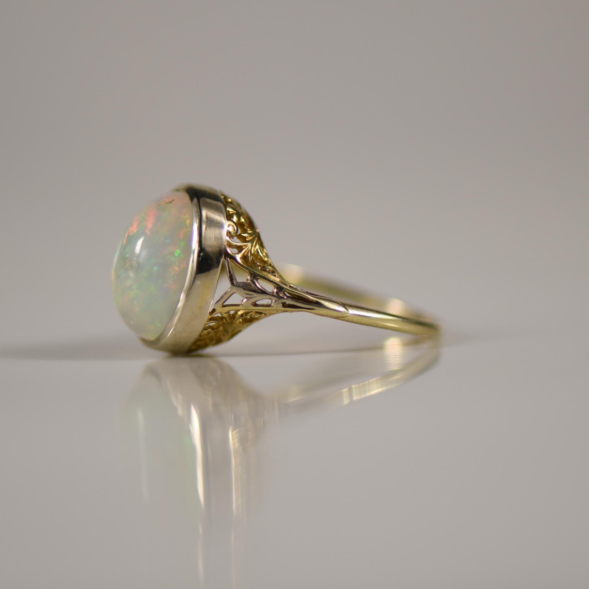 This piece is ethereal, the center opal has a subtle deep fire that lights up the stone with every twist and turn. Flashes or orange and green dance across this gem with ease. Delicately placed in a white gold bezel, the shanks with yellow gold