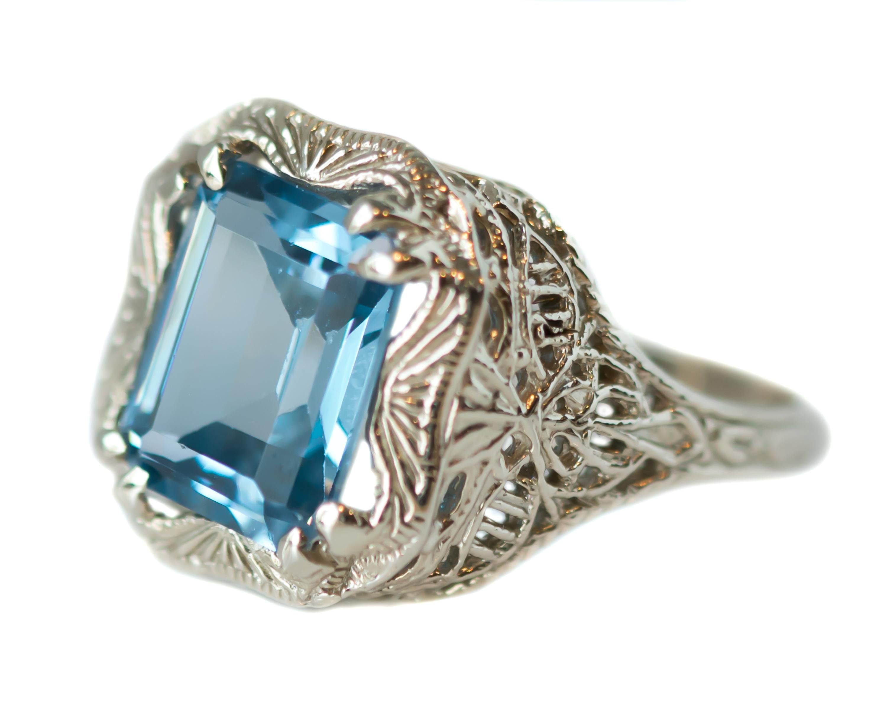 1920s Art Deco 3 carat Blue Topaz Ring - 14 Karat White Gold, Blue Topaz

Features:
3 Carat Emerald cut Blue Topaz
14 Karat White Gold Filigree Setting
4-Prong Setting
Open Filigree Gallery and Shoulders
Shank tapers to 1.75 millimeters at center
