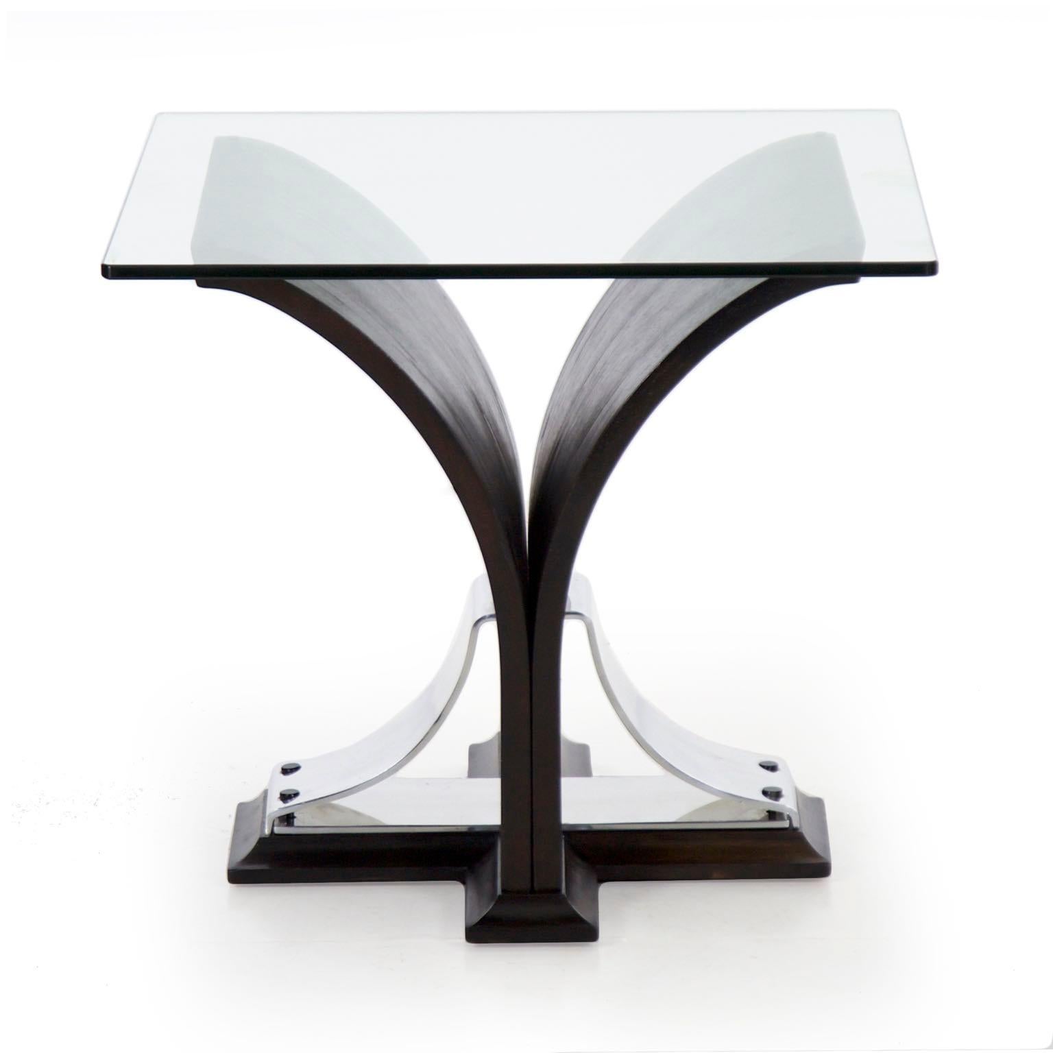 An interesting table from the second quarter of the 20th century with an ebonized walnut veneer steam bent into a sprouted form over a solid cove molded base supported by curved aluminum and locked together with chromed steel screws under a thick