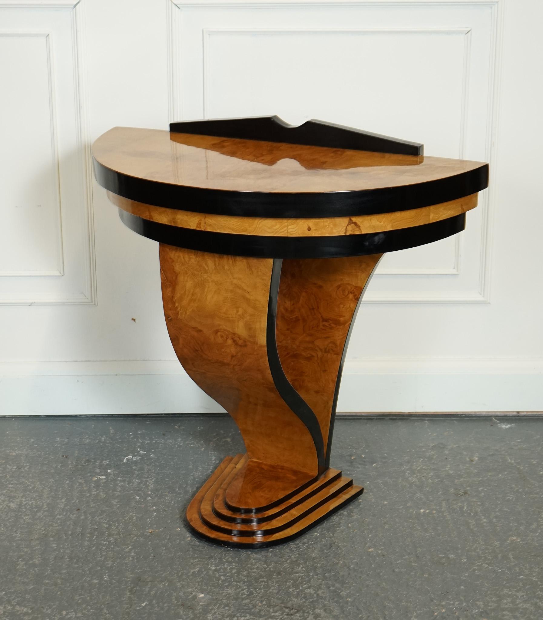 
We are delighted to offer for sale this Ebonised Art Deco Style Burr Walnut.

The Art Deco Burr Walnut with Black Trim Demi Lune Console Hall Table is a stunning piece of furniture that embodies the sleek and glamorous style of the Art Deco era.
