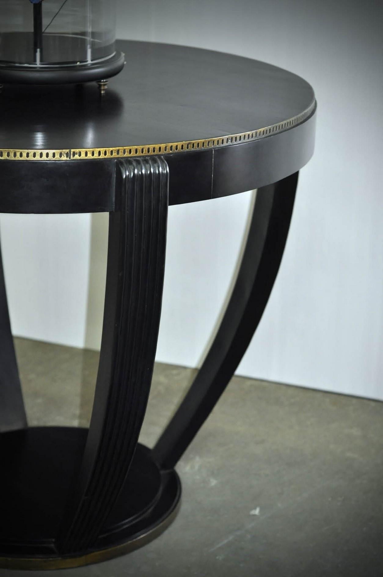 192s Art Deco design round pedestal table consisting of a graphic and geometric black wooden structure adorned with a brass inlay.