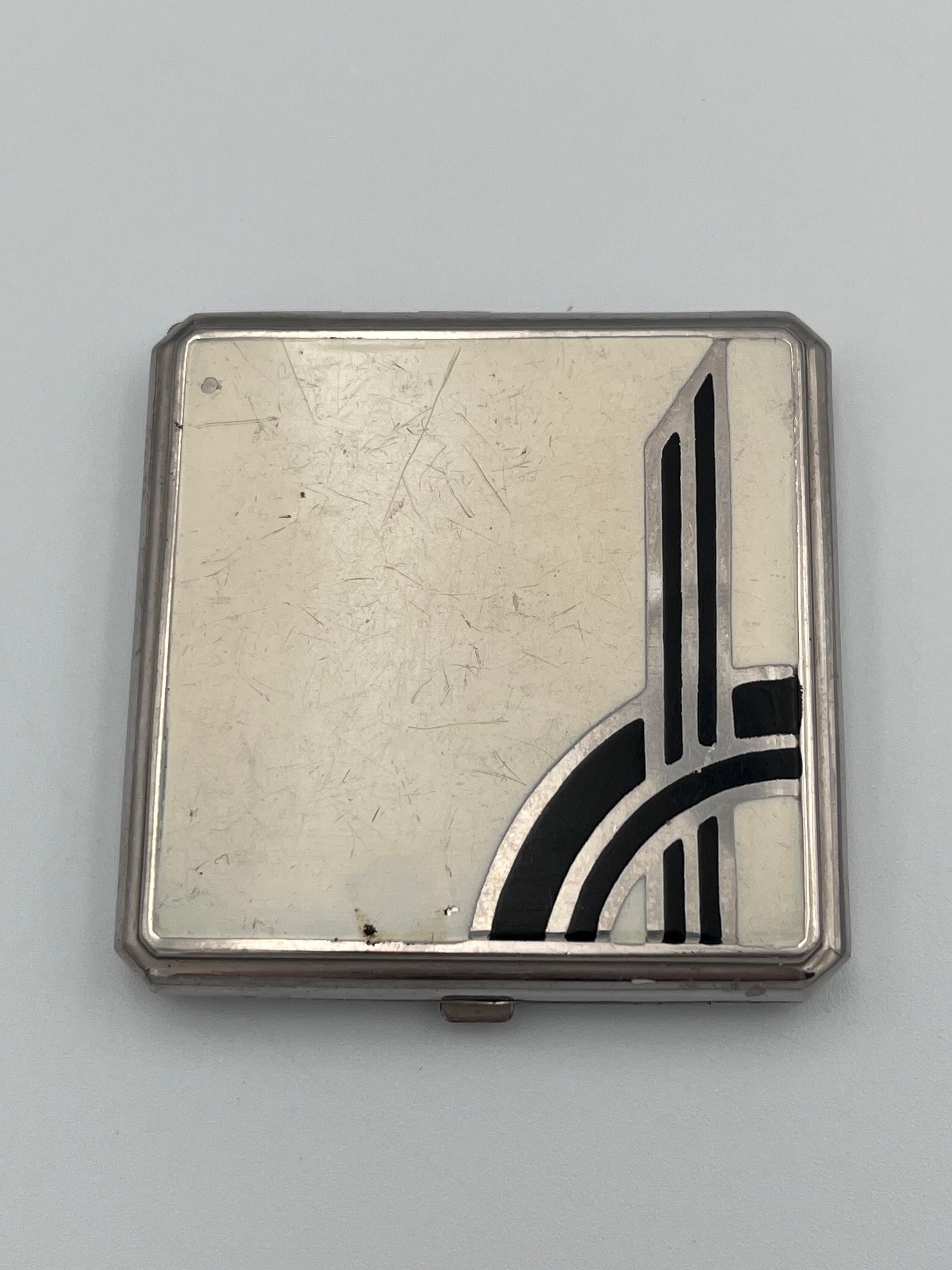 1920s Art Deco Enamel Ladies Makeup Compact Mirror with Rouge, Mirror, and Powder Puffs

A striking and authentic 1920s Art Deco enamel ladies makeup compact, featuring a beautifully asymmetrical ivory and black geometric design on the lid, a