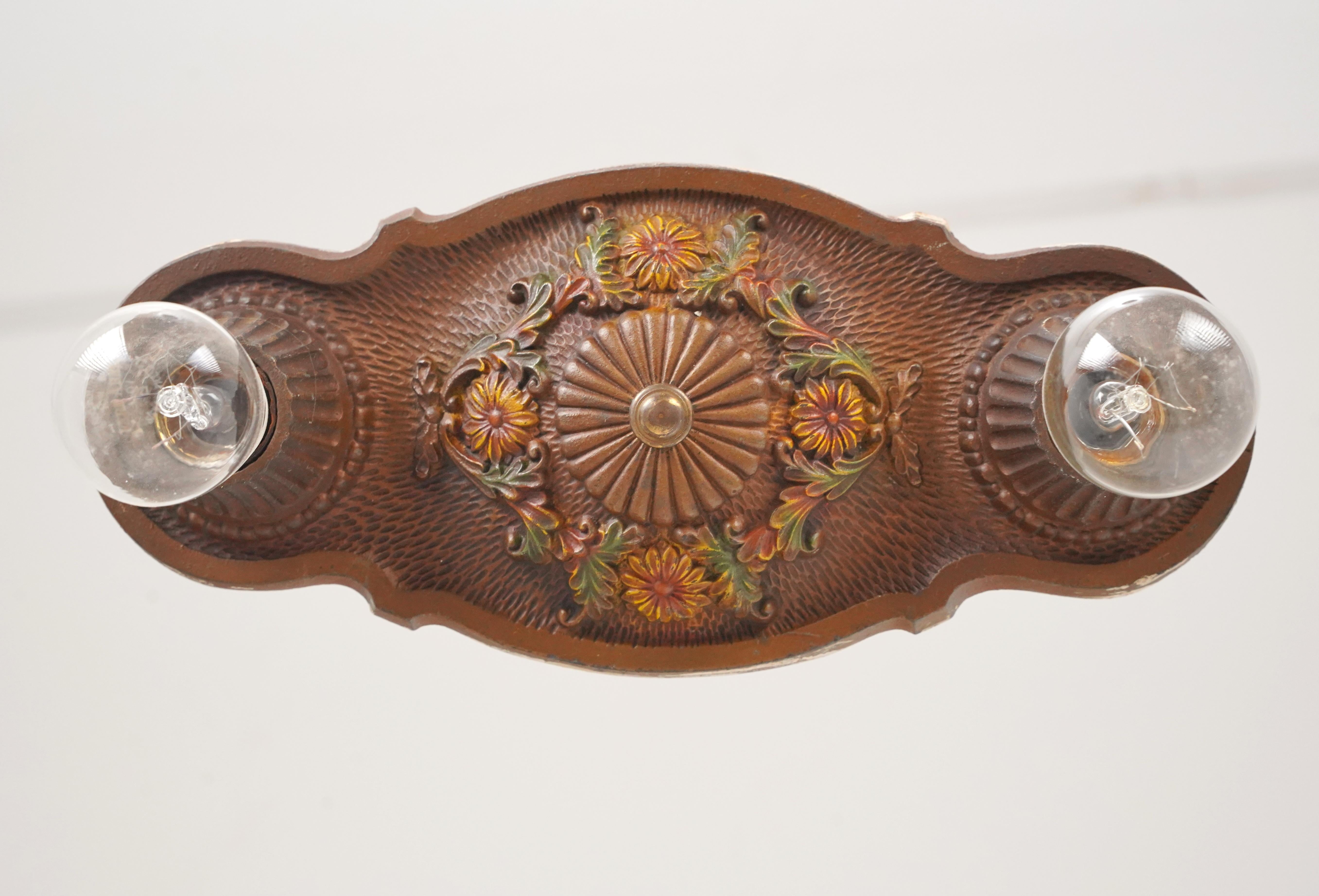 Unterputzleuchte im Art-Déco-Stil der 1920er Jahre mit erhabenen, bunten Blumenmustern und geriffelten Lampenfassungen. Er besteht aus Gusseisen mit einer dunklen Bronzeoberfläche. Benötigt werden zwei normale Edison-Glühbirnen mit mittlerem Sockel.
