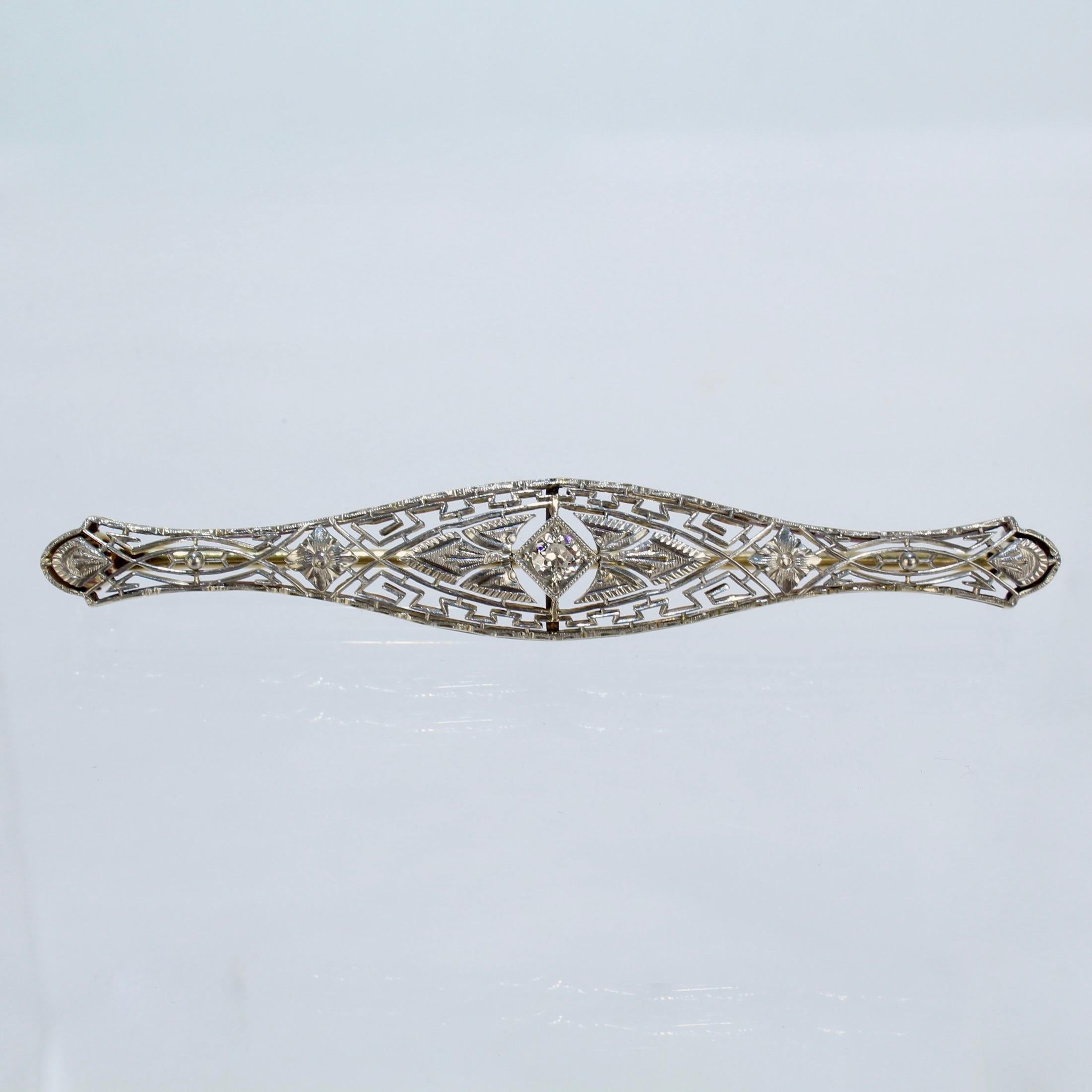 A fine Art Deco 14k gold and diamond filigree bar pin.

With a ca. .15 ct round cut diamond in an ornate filigree setting.

The front of the pin is rhodium plated.

Marked 14K on the clasp.

Length: ca. 64 mm

Items purchased from this dealer must