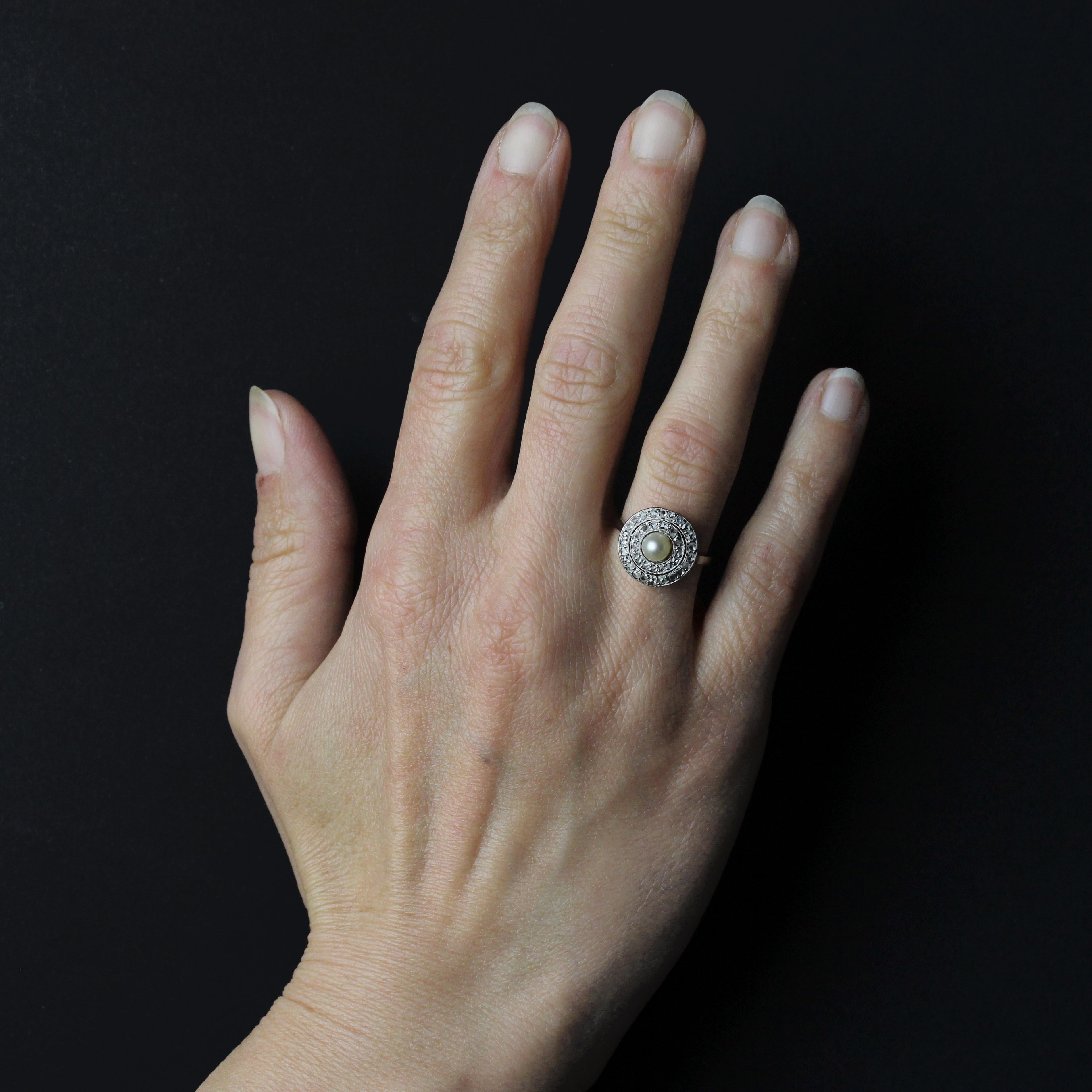 Anello in platino.
Un affascinante anello antico in platino, la cui montatura rotonda è traforata con motivi geometrici. Sulla parte superiore, una perla rotonda color crema perlato adorna il centro di una doppia fila di diamanti con taglio a
