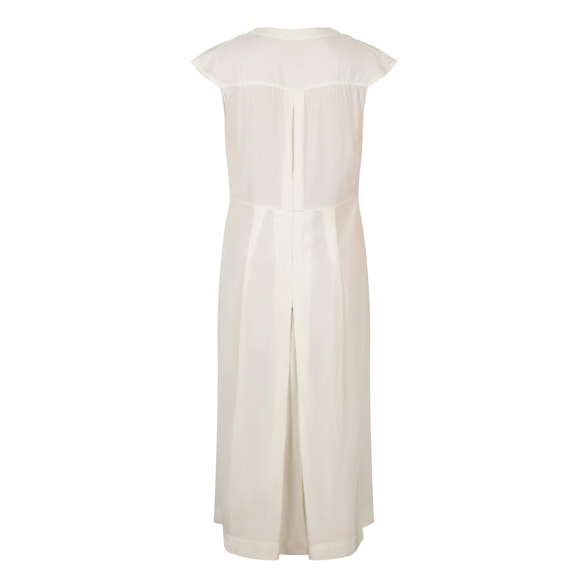 Cette élégante robe art déco en soie crème des années 1920 est de très bonne facture et extrêmement bien conservée. Elle présente des détails typiques de l'époque, notamment le style blouson chemise et le porte-bouton central décoratif. La patte de