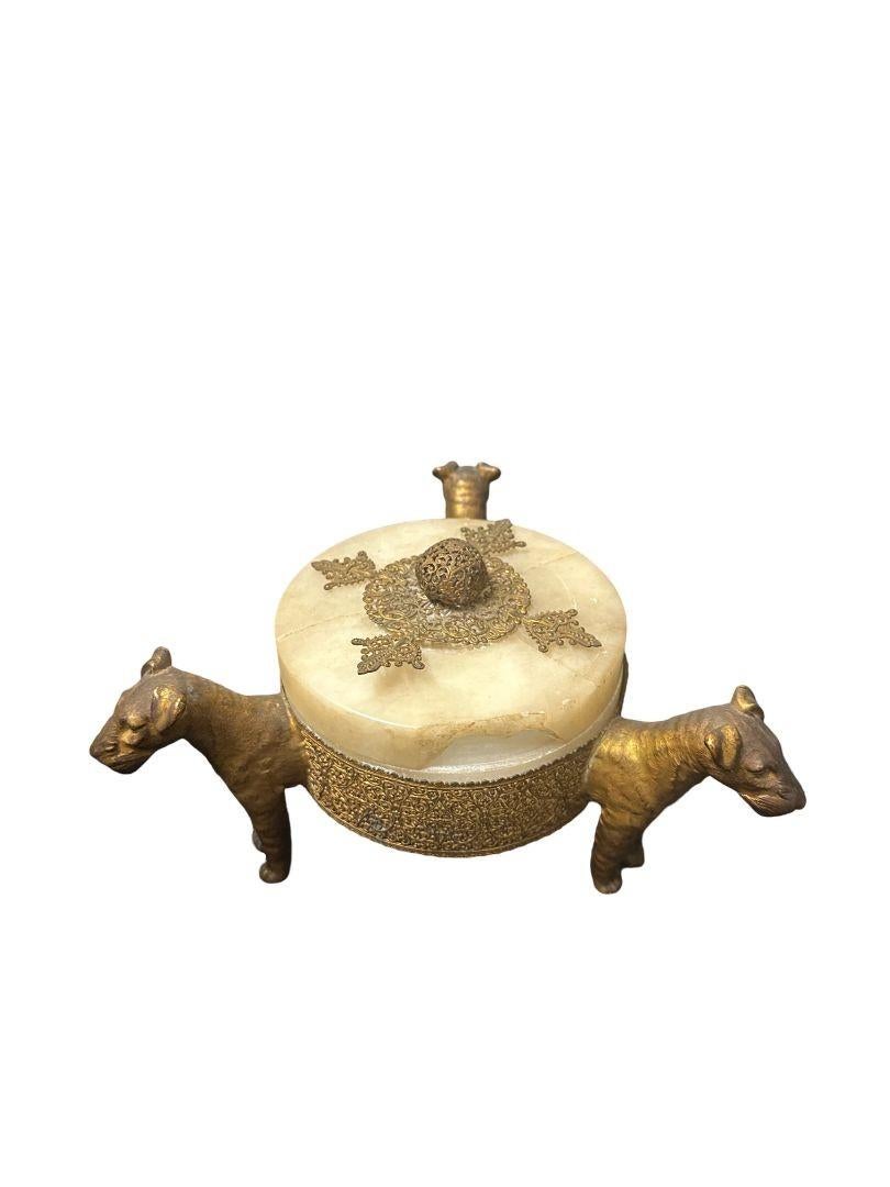 This exquisite Vintage Jewelry Box in Brass is a unique and rare find, showcasing intricate detailing of three terrier dogs. Crafted from a blend of brass and alabaster, this piece exudes a timeless charm that adds a touch of sophistication to any