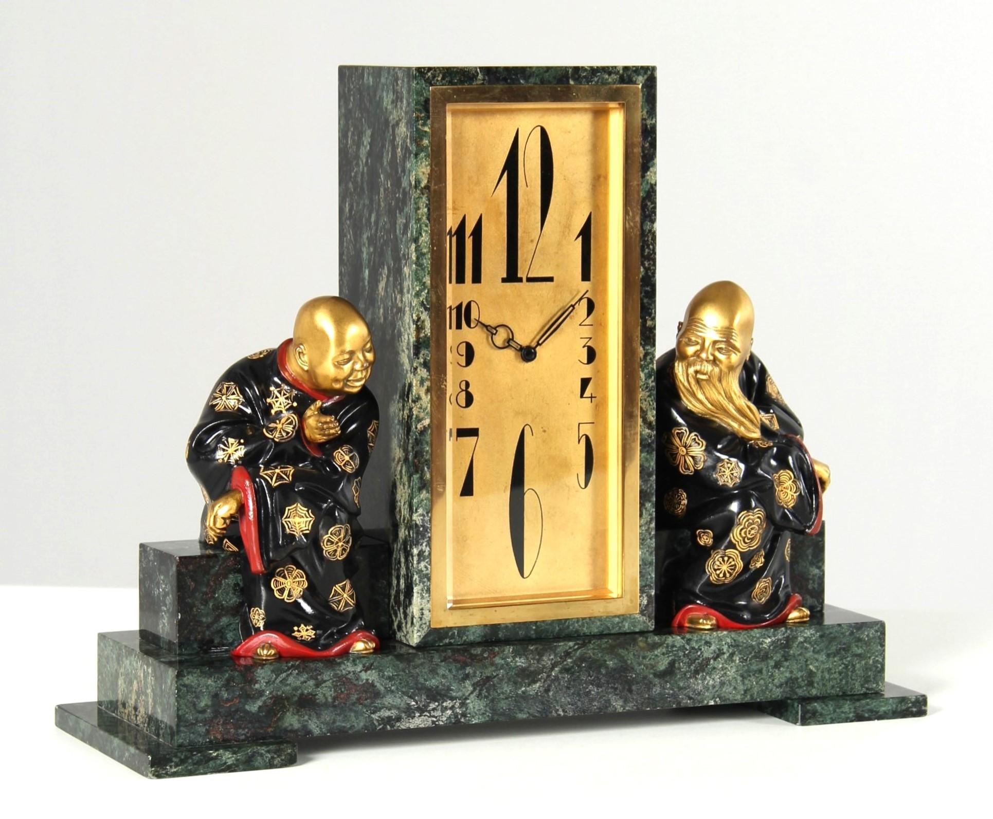 Chinoiserie Art Deco Mantel Clock

France
Bronze, serpentine
1920s

Dimensions: H x W x D: 27 x 34 x 12 cm

Description:
A stele rises from the centre of a stepped base made of green serpentine. The bezel is set flush into the stone. Behind the