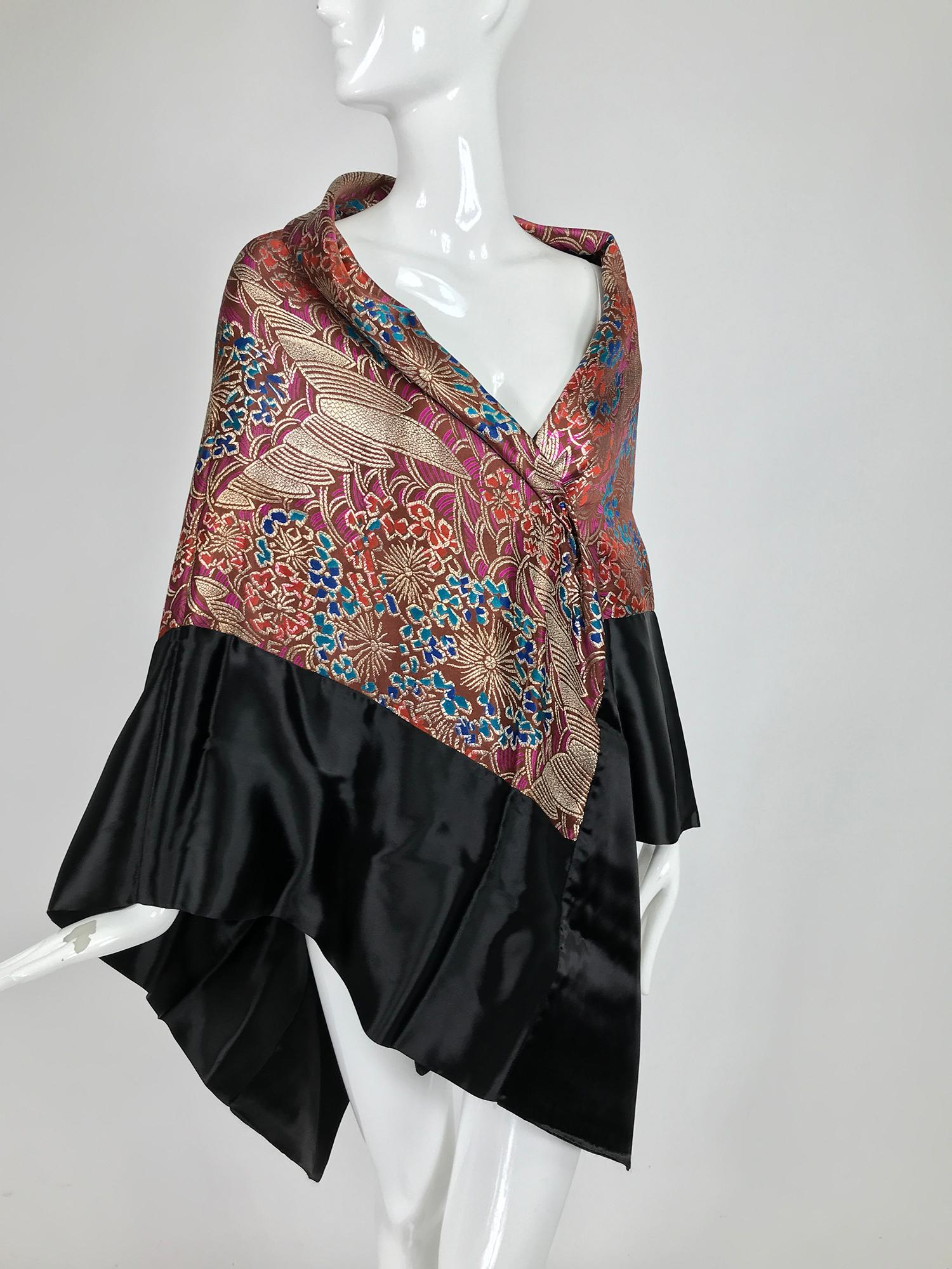 1920s Art Deco metallic brocade square shawl with black satin border. 
A beautiful shawl with an inset of 1920s metallic silk brocade that features Art Deco motifs. Deep wide border of black satin. The back of the shawl has some oxidation marks