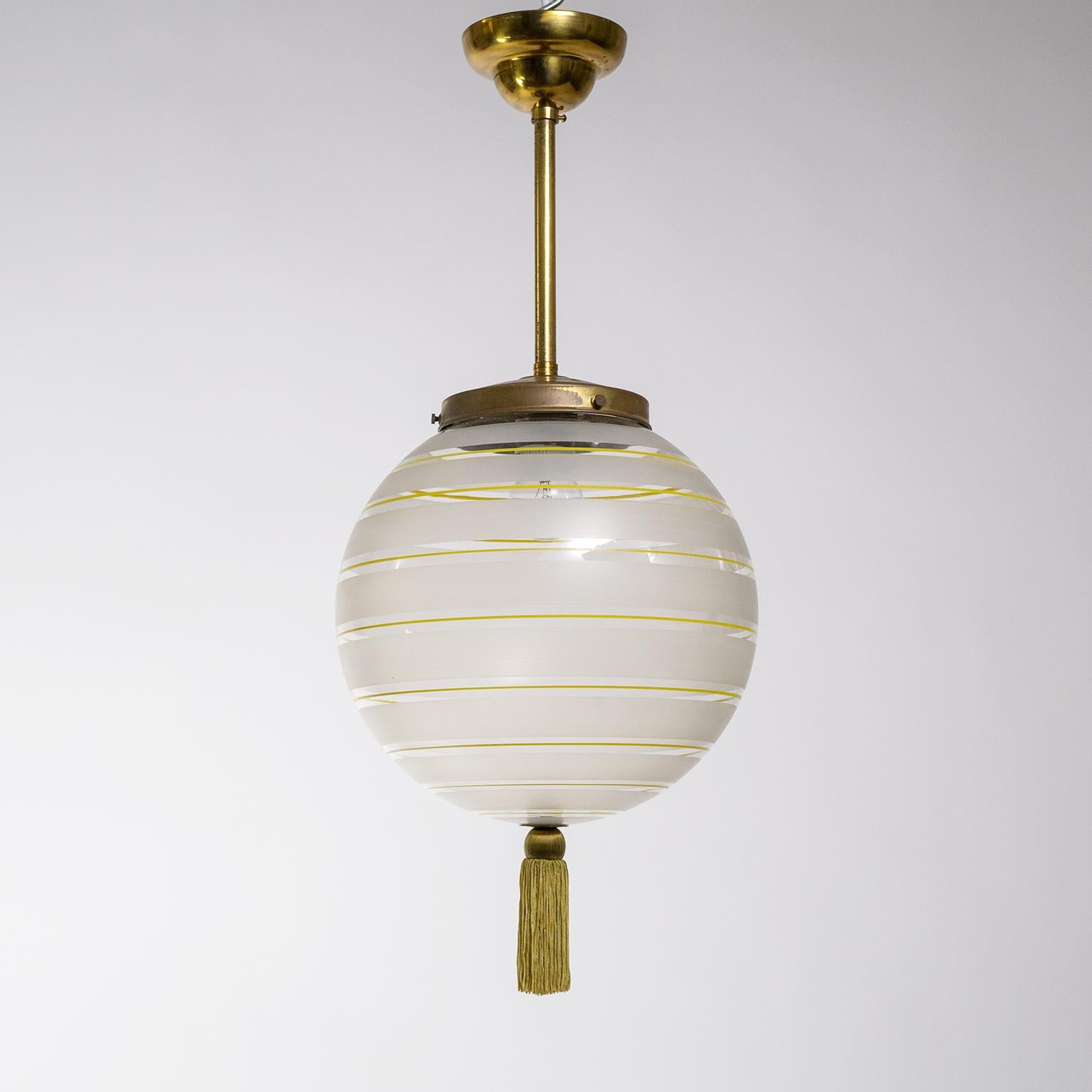 Beautiful 1920s Art Deco pendant with a blown clear glass globe and brass hardware. The glass diffuser has broad etched stripes alternating with thin hand painted yellow stripes as well as a tassle on the bottom. Excellently executed and in very