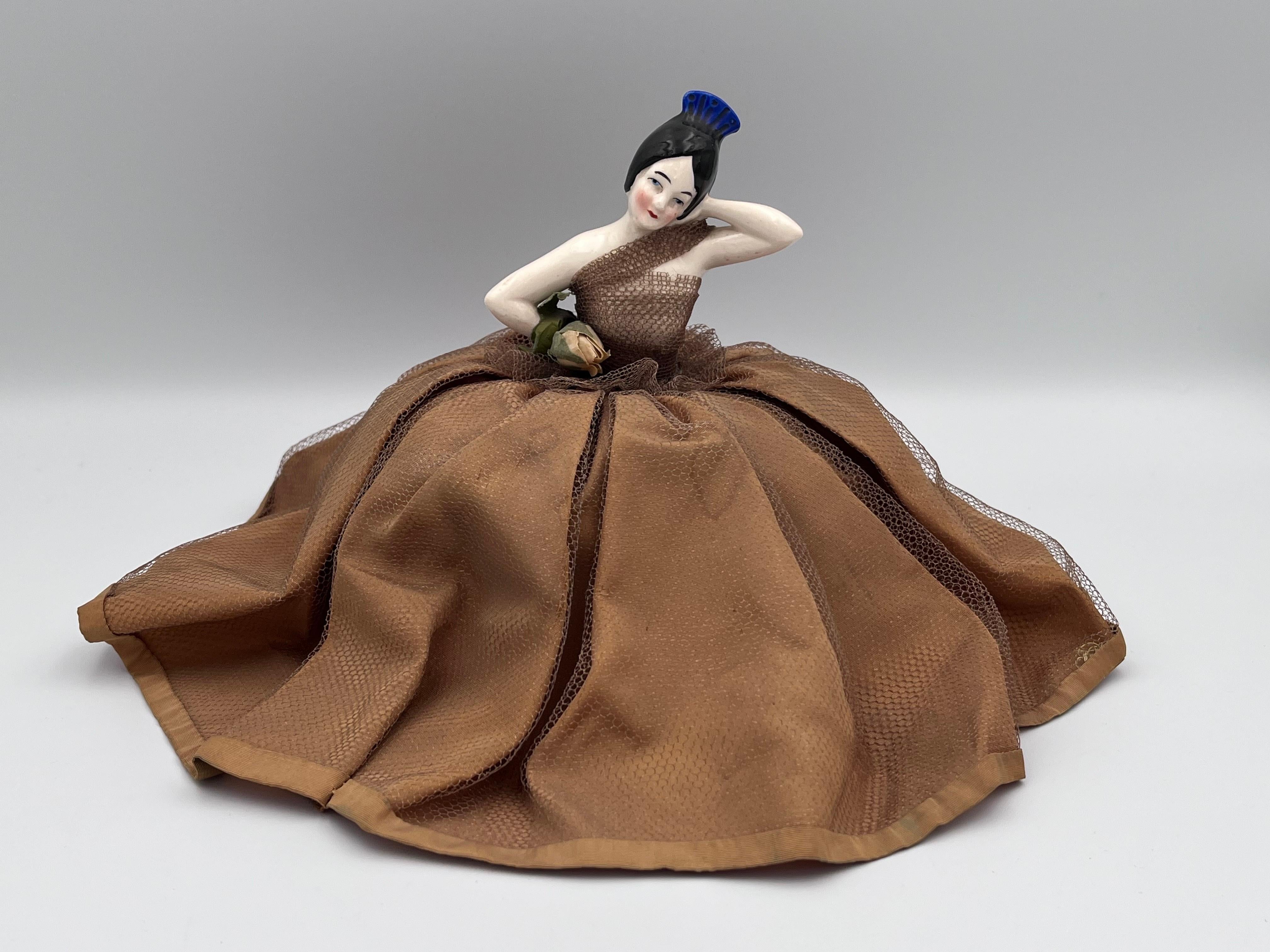 Demi-poupée danseuse espagnole en porcelaine Art Déco des années 1920 avec socle à coussin d'épingles

Cette étonnante demi-poupée en porcelaine Art déco des années 1920 représente une danseuse espagnole dramatique, magnifiquement coiffée d'un