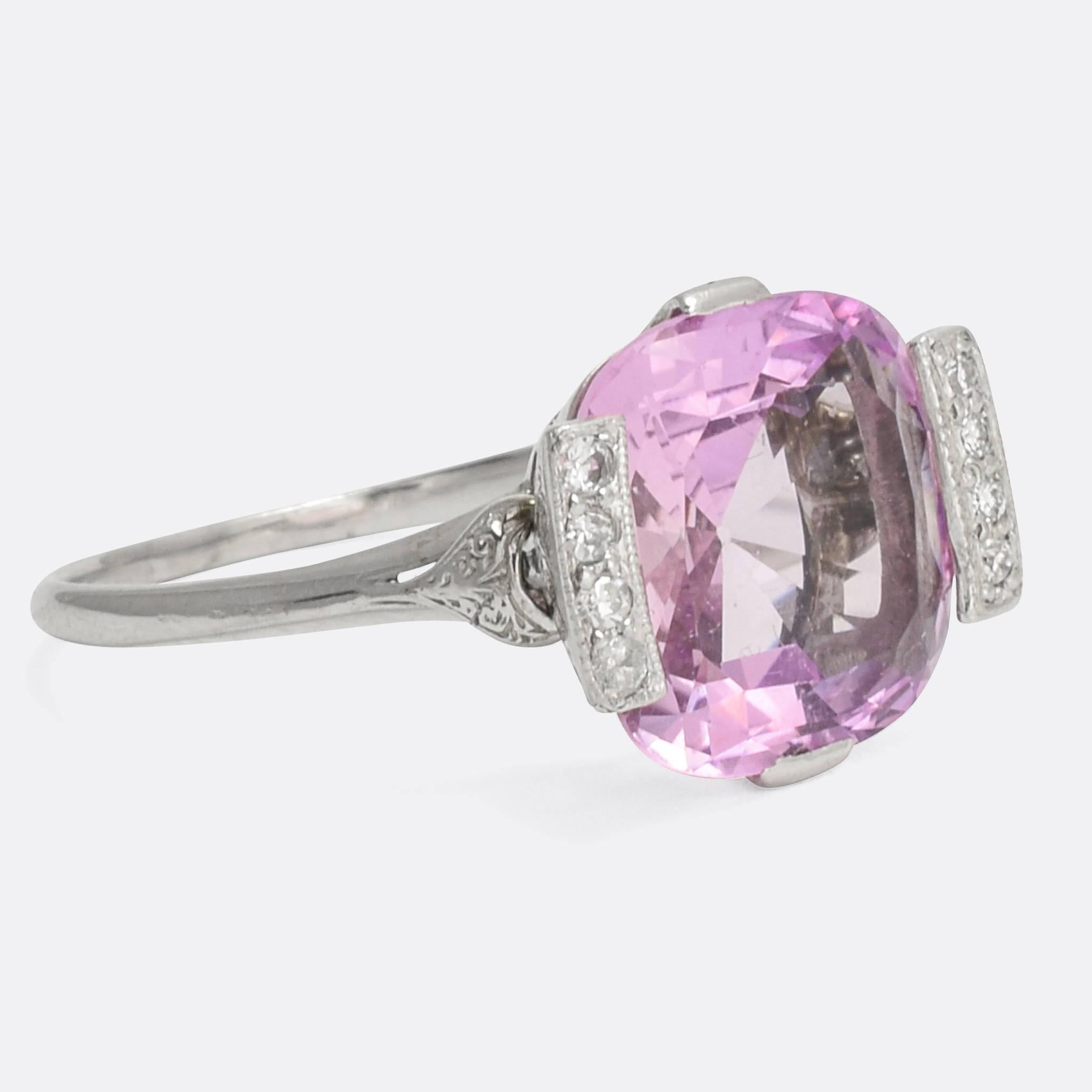 A spectacular Pink Topaz cocktail ring dating from the Art Deco era, circa 1920. The principal 6.5 carat stone is a dreamy pale pink colour, framed by two rows of white diamonds in millegrain settings. Modelled in platinum throughout, with unusual