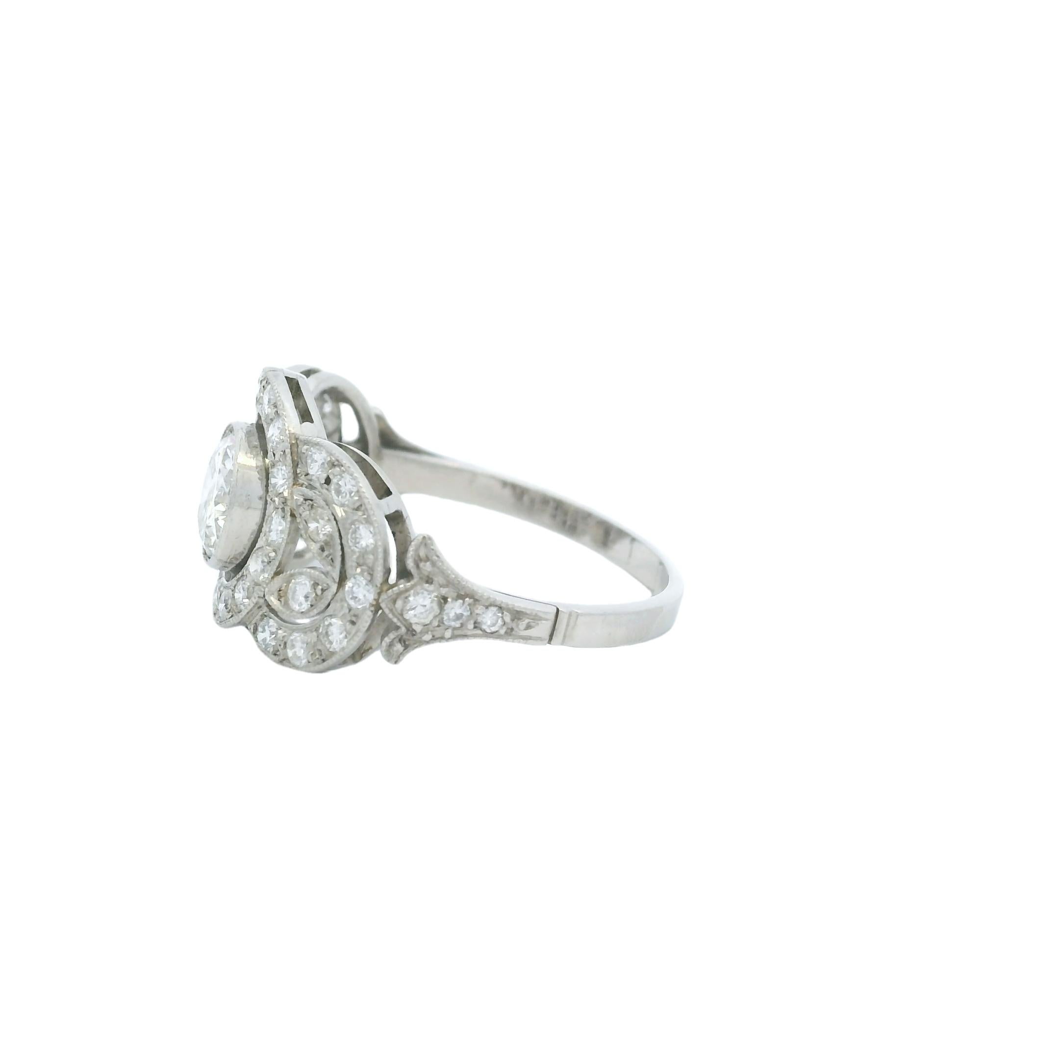 Este exquisito anillo de diamantes Art Decó de platino de los años 20 capta la esencia de la atrevida elegancia y la meticulosa artesanía de la época. En el centro hay un deslumbrante diamante redondo de talla brillante de 0,85 quilates, engastado