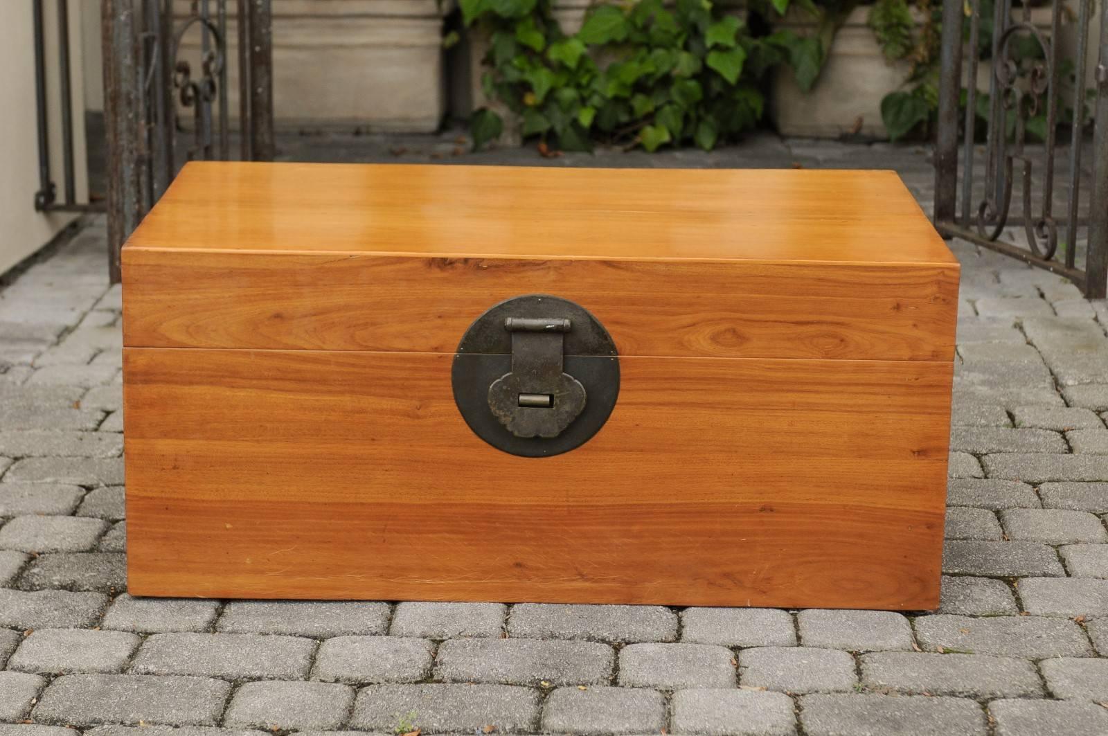 An Asian camphor wood box from the early 20th century, with traditional lockset on medallion and lateral handles. This Asian camphor trunk features a clean, rectangular shape, simply accented with metal hardware and dark dovetails on the side