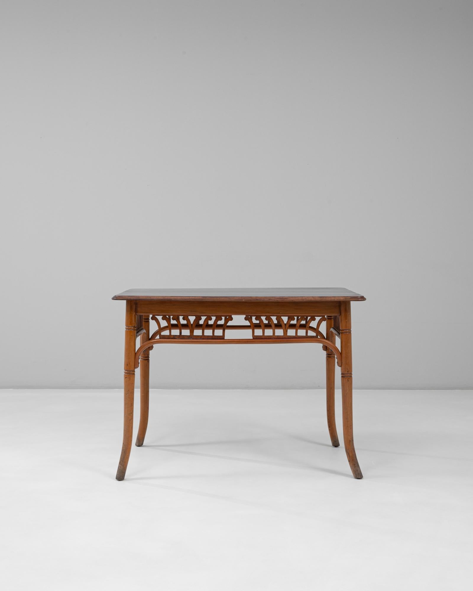 This 1920s Austrian Art Nouveau bentwood side table exemplifies the graceful curves and organic forms characteristic of the period. Crafted from warm-toned wood, the table features elegantly arched supports beneath the apron, showcasing the refined