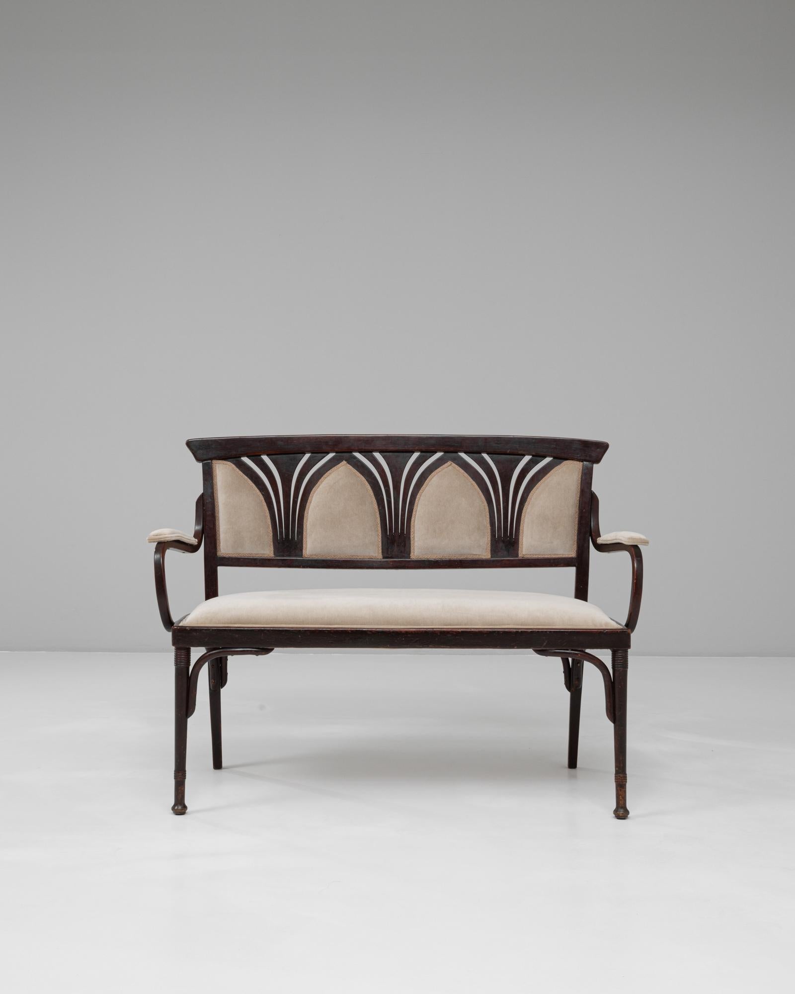 Este sofá de estilo gótico austriaco de los años 20 combina la elegancia arquitectónica con la artesanía atemporal. Fabricado en madera teñida de oscuro, tiene un respaldo elegantemente arqueado con intrincados recortes de inspiración gótica que