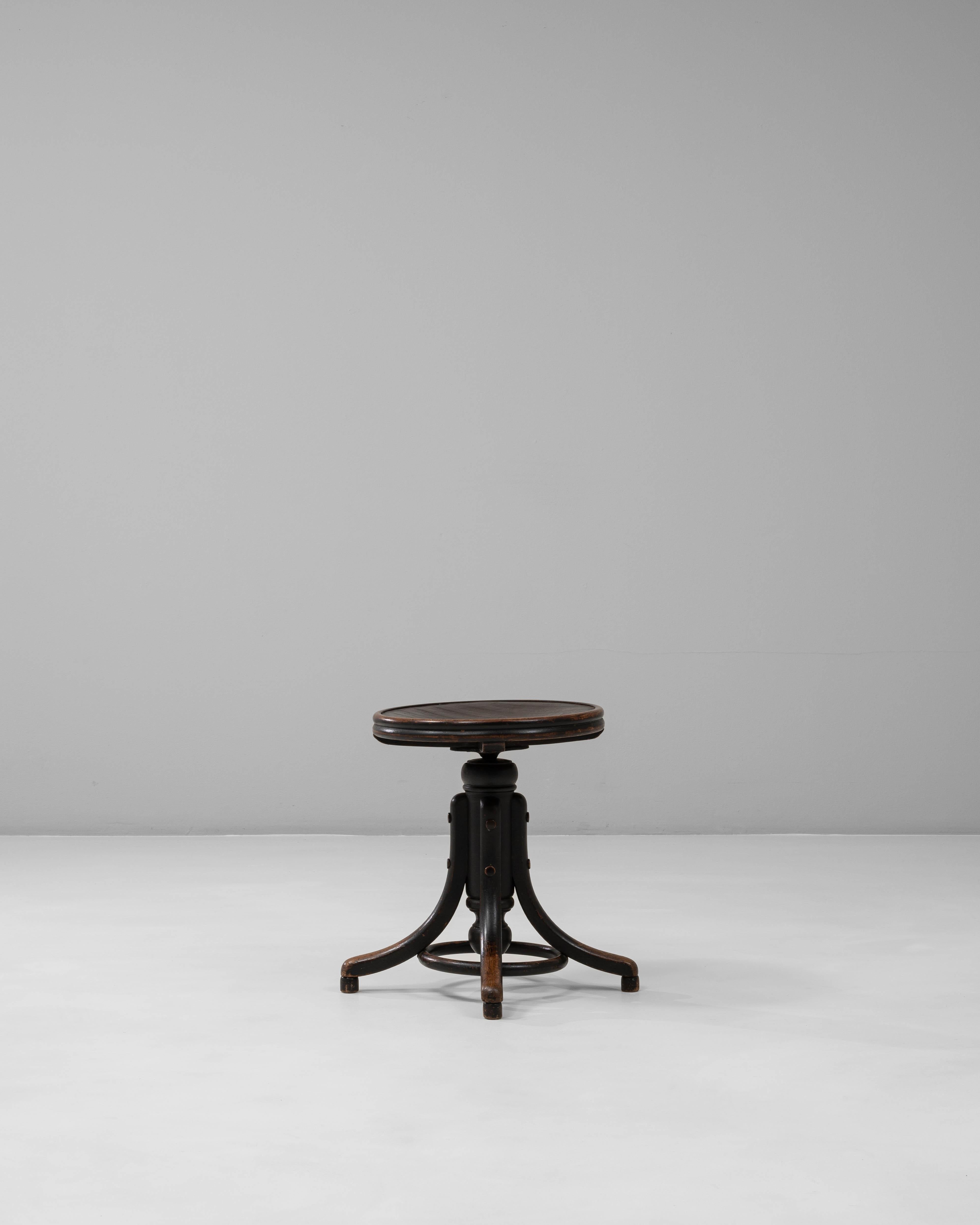 Ce tabouret pivotant en bois industriel autrichien des années 1920 présente un design robuste et utilitaire qui reflète l'artisanat d'atelier du début du XXe siècle. Le siège circulaire repose sur une colonne centrale dotée d'un mécanisme de