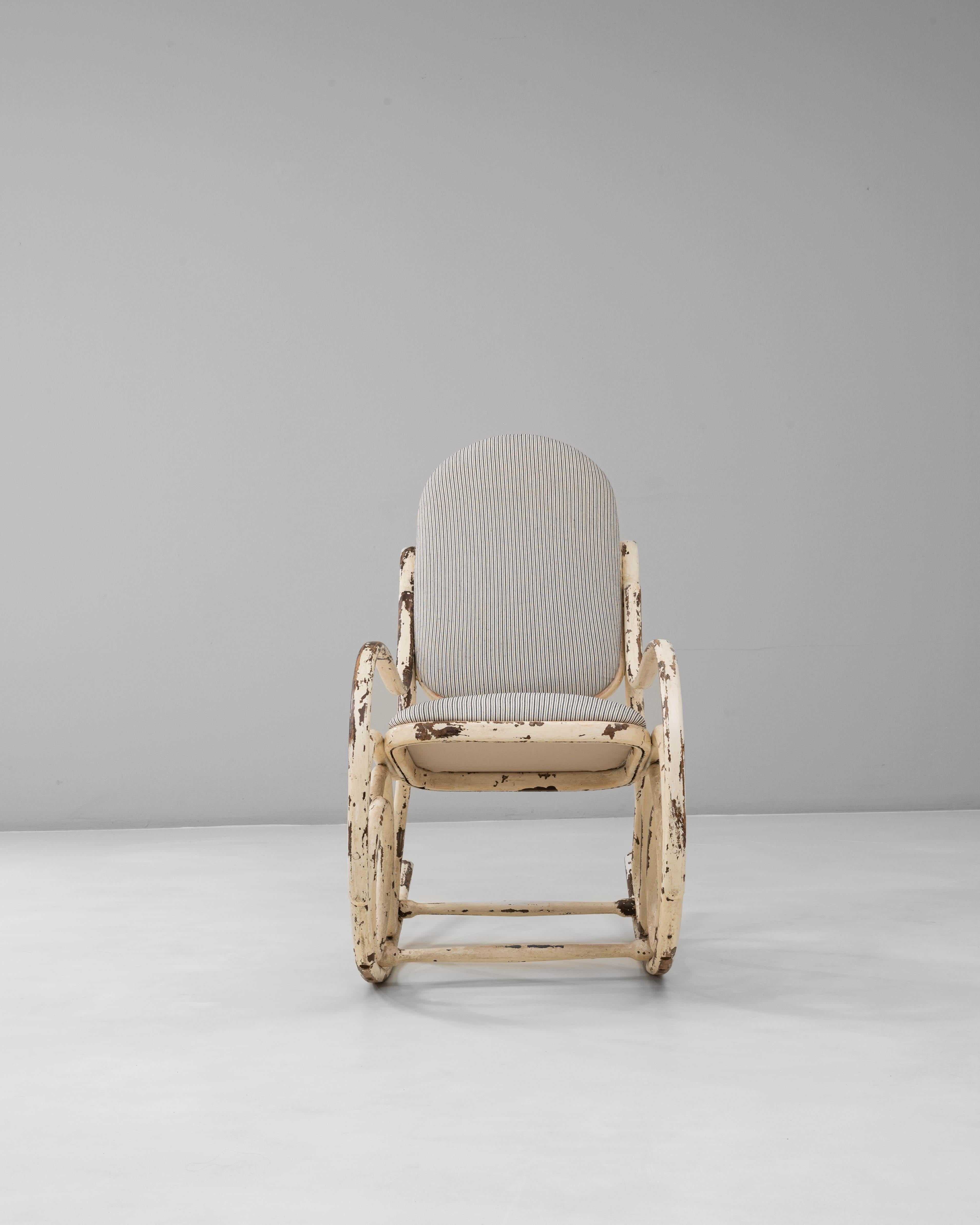 This 1920s Austrian Thonet-style bentwood rocking chair embodies the graceful curvature and lightness associated with classic Viennese design. Crafted from steam-bent wood, the frame features elegant, looping lines that flow seamlessly from the high