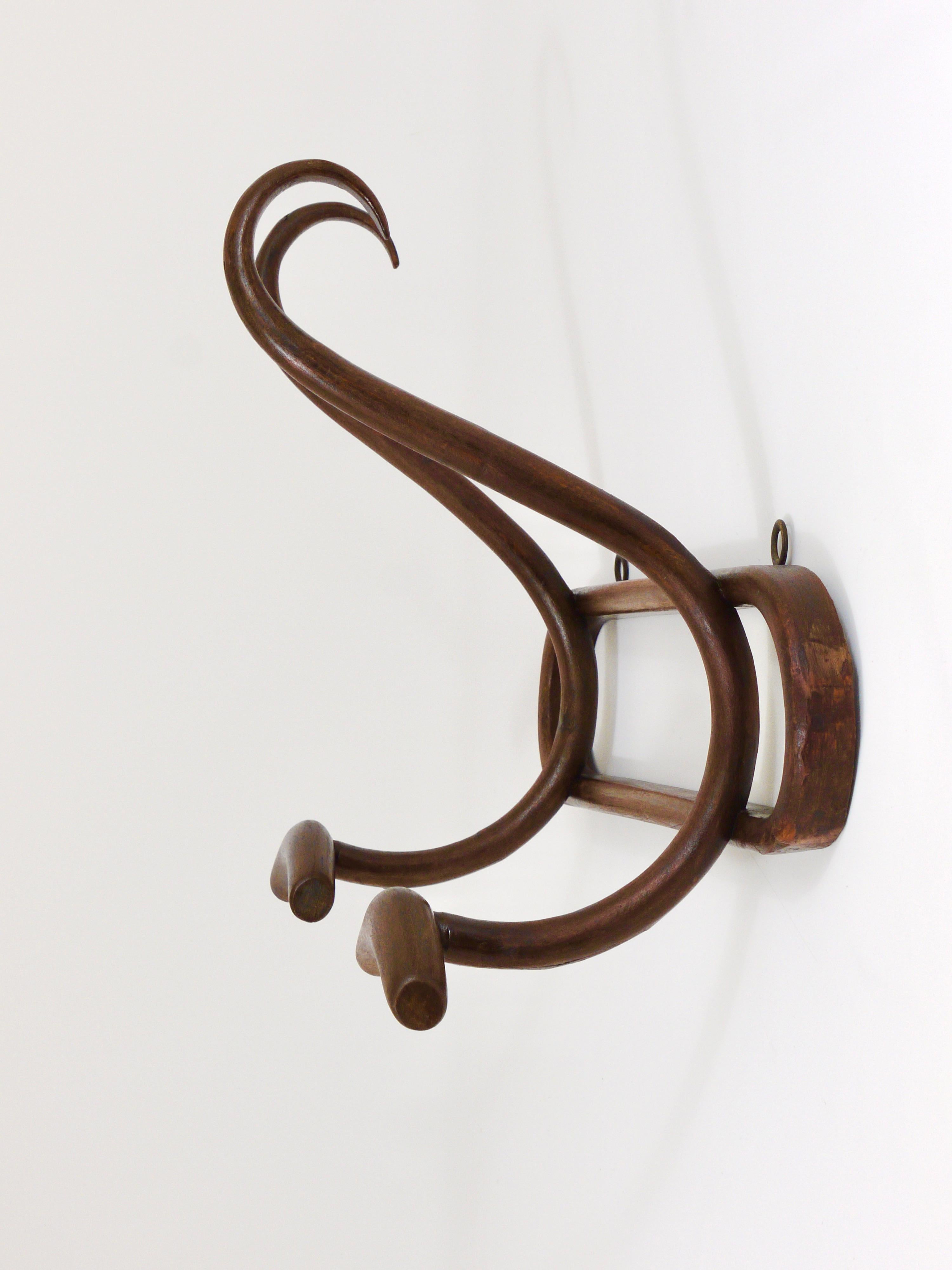 A beautiful brown Art Nouveau wall-mounted coat and hat rack from the 1920s by Joamin Baumann for Baumann France. Made of bentwood, with two S-shaped hooks. In good condition with patina.