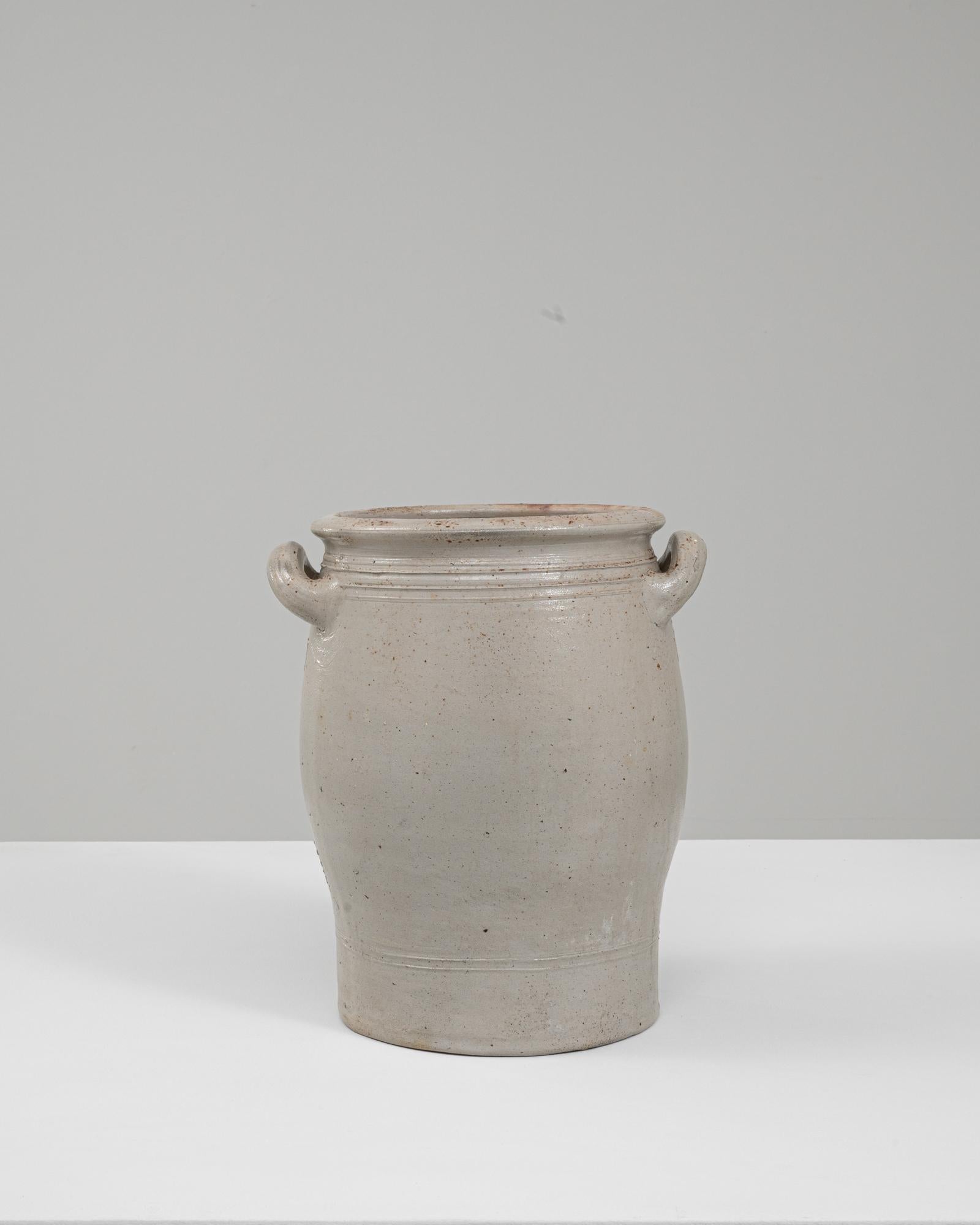 Questo vaso in ceramica belga degli anni '20 incarna la sobria utilità e l'artigianato regionale tipico del gres dell'inizio del XX secolo. La sua silhouette dolcemente arcuata, che si allarga nella parte centrale prima di assottigliarsi verso una