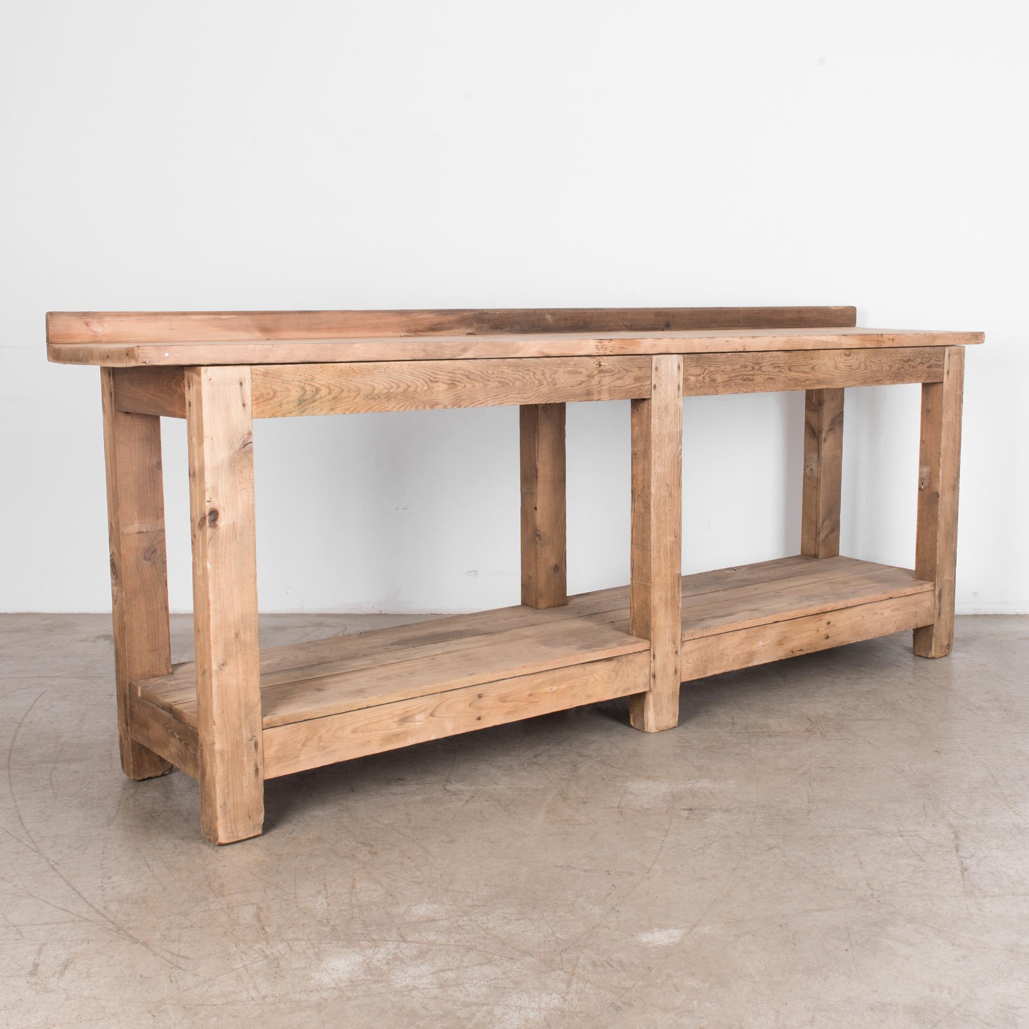 From Belgium circa 1920, a heavy duty wooden table. A weathered finish, for a room that needs character. Equipped with a practical and structural lower shelf, all supported by a sturdy frame and thick legs, realized in natural finished softwood,