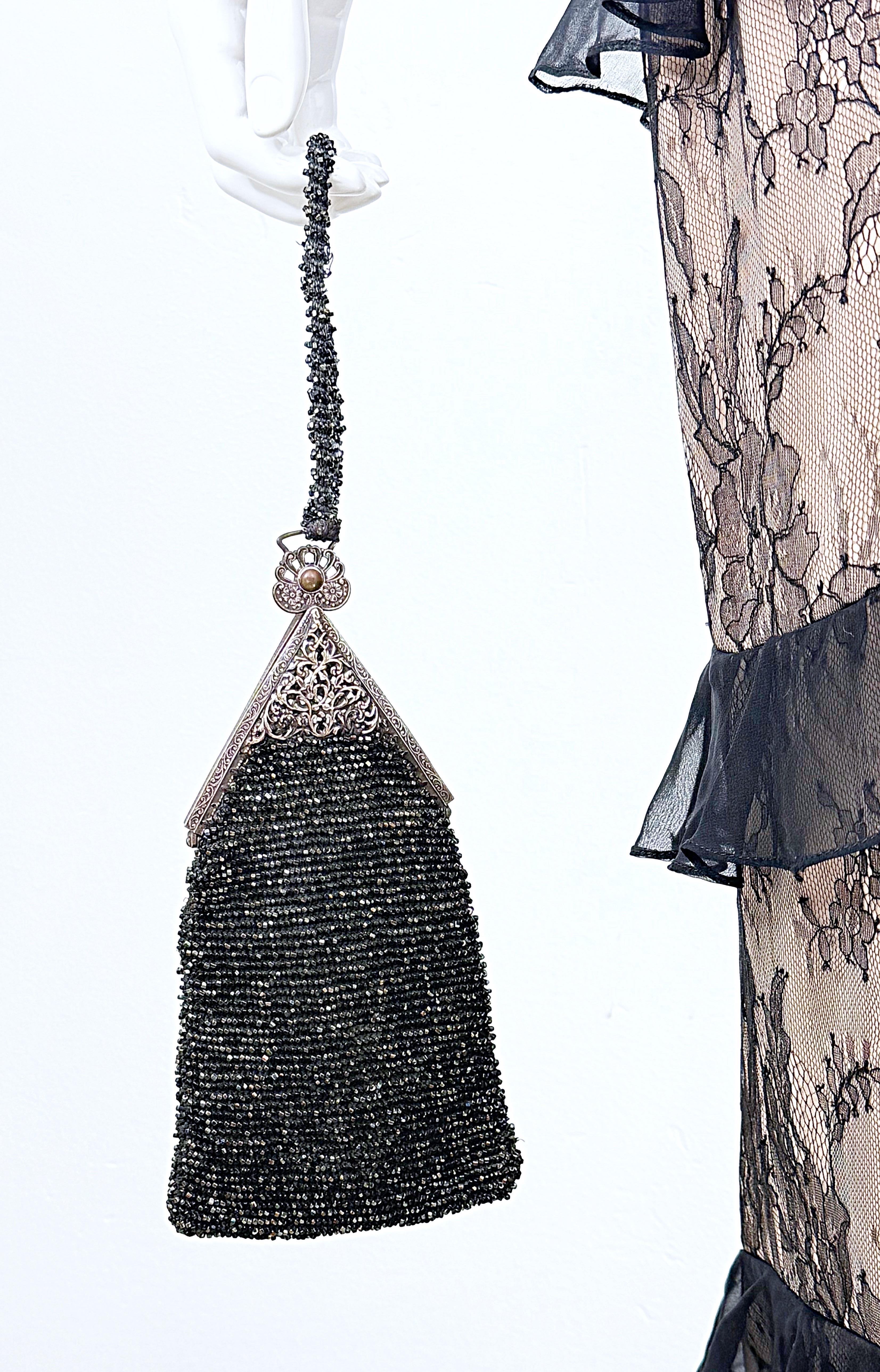 Exquisite 1920s handmade black silk beaded triangular evening wristlet bag ! Includes a note that says;
Made by Nellie Challand in 1925. Given to Virginia Fourrier on August 12, 1975. 
Silver frame with clasp closure. A wonderful piece of fashion