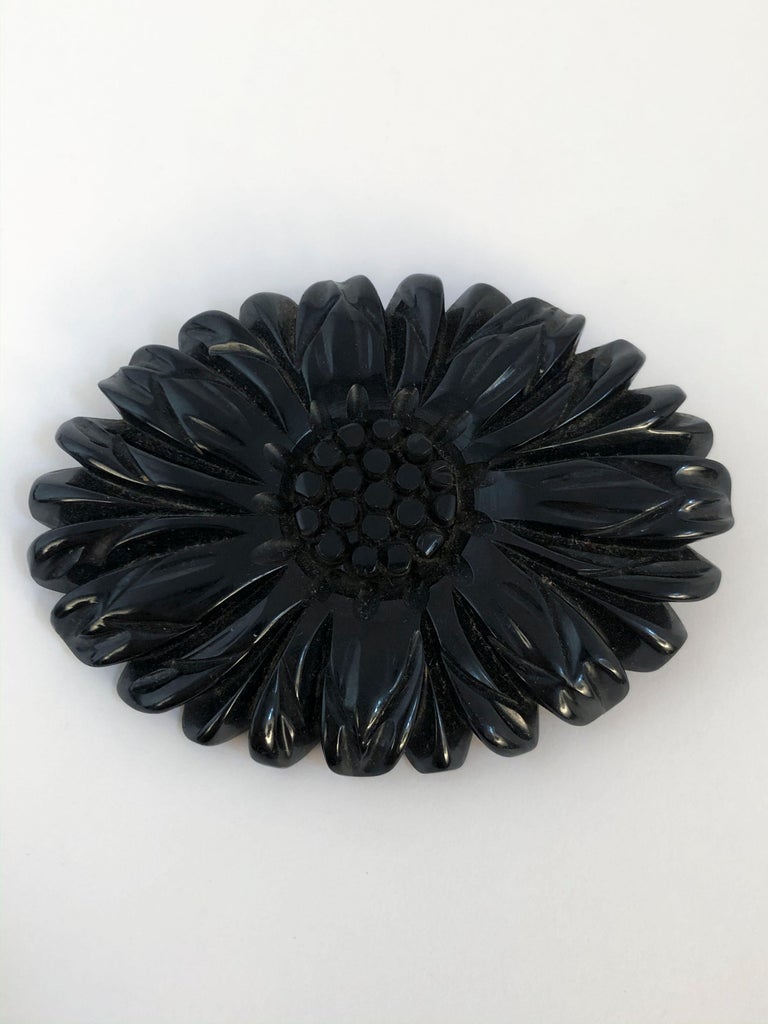 Black mourning bakelite brooch that features a hand-carved floral motif. Long secured hook and pin fastening on the back