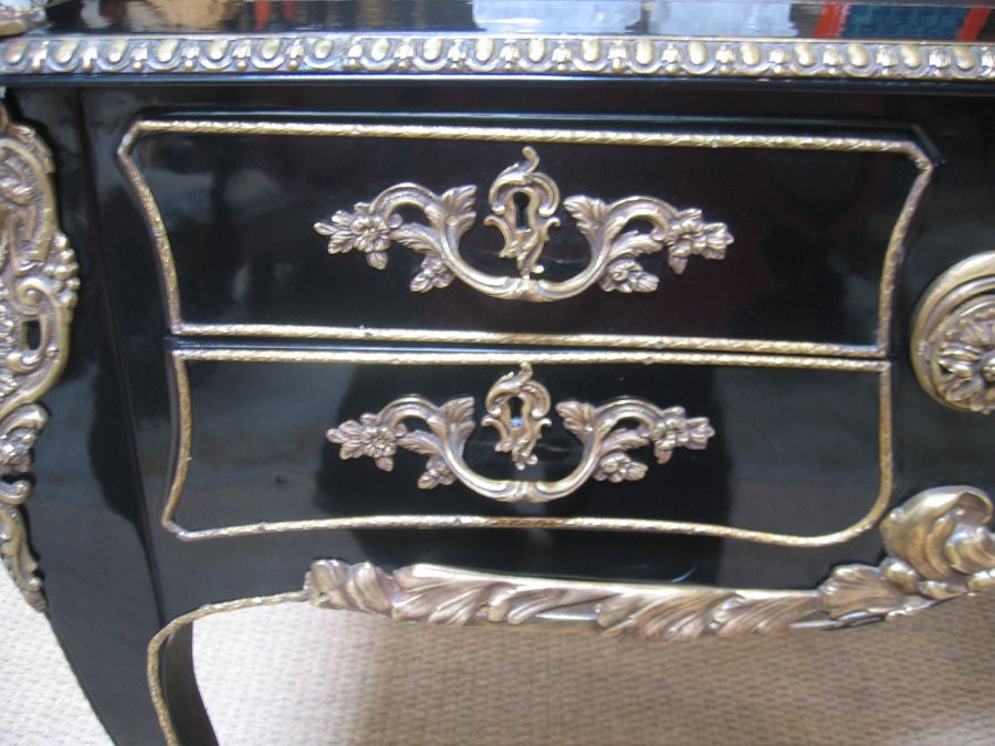 1920s black lacquered French desk with black leather inset writing surface. Beautifully detailed with ormolu mounts. Details feature Greek motifs and rococo styled hardware.