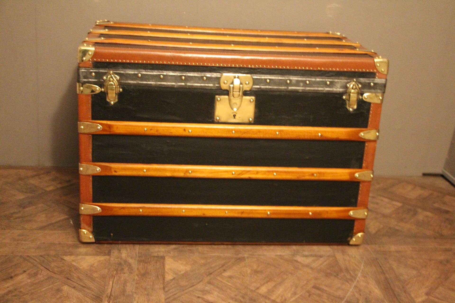 This nice steamer trunk features black canvas, honey color lozine trim, large leather side handles and brass corners and locks.
Yellow and blue stripes of customization on the sides..
Its main lock as well as its handle latches are marked 