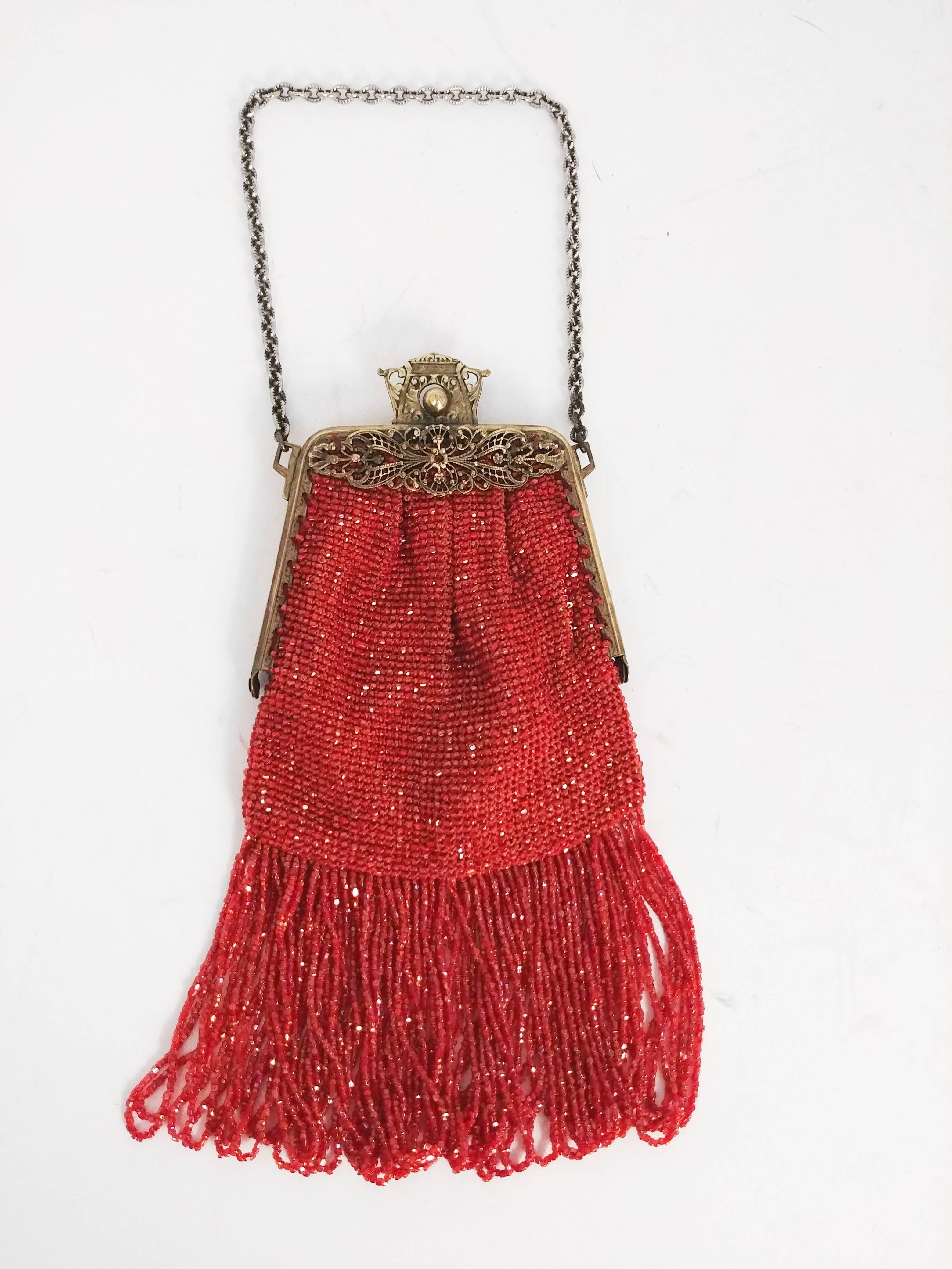 1920s Blood Orange Glass Bead Fringe Purse. Intricate filigree clasp and frame, chain link handle. Looped glass bead fringe trim. Brightly printed floral lining adds surprise pop of color. 