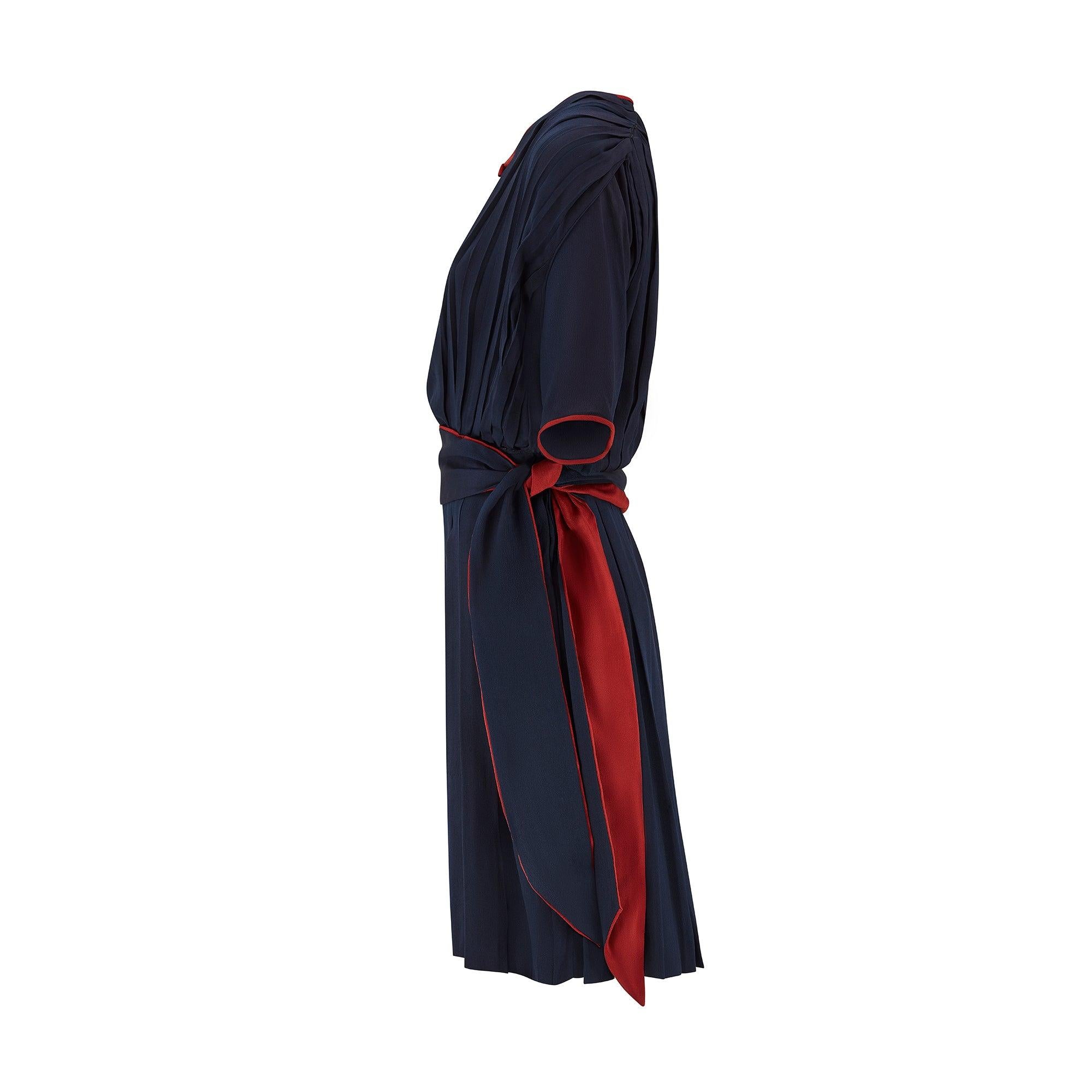 This elegant and original vintage 1920s day dress is cut from a beautifully made navy blue silk crepe and trimmed with vibrant russet red. Designed to look like a co-ordinated two-piece ensemble, the dress is couture made with mostly hand-sewn