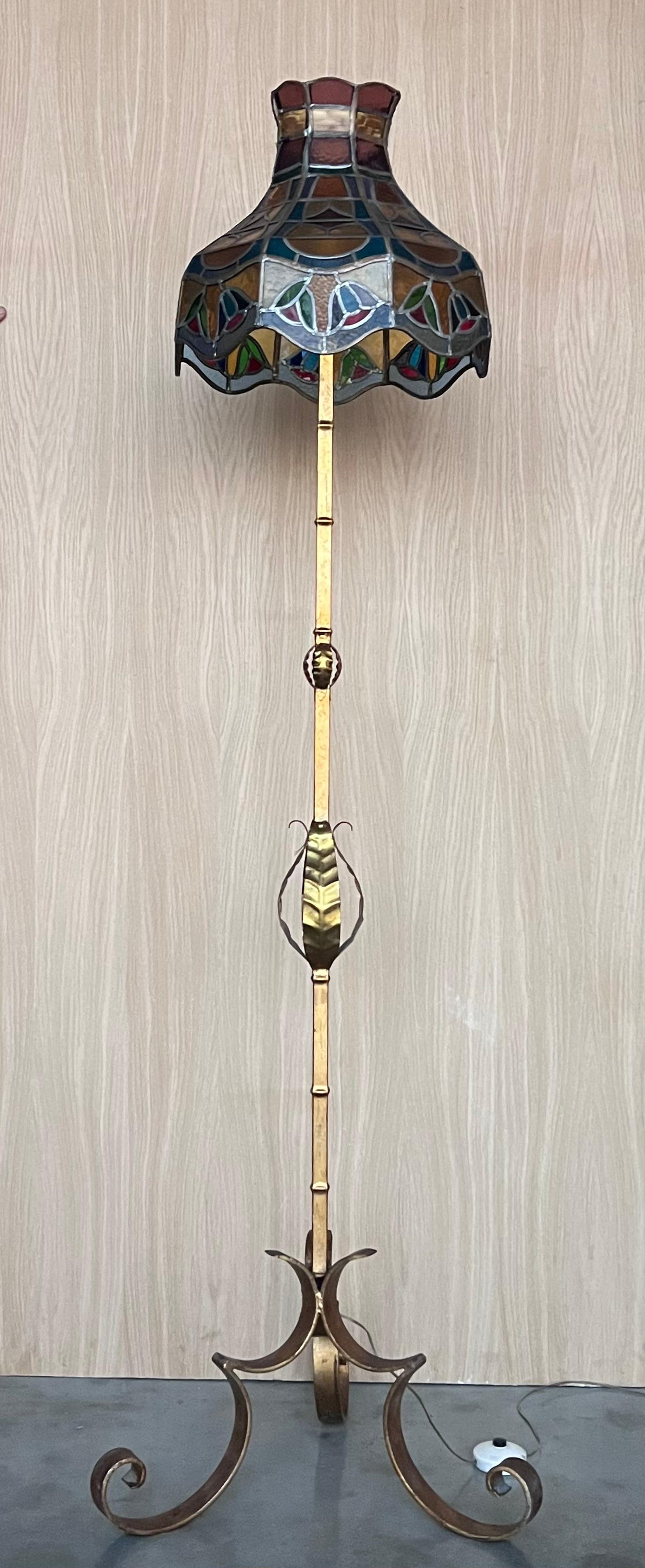 Lampadaire ancien des années 1920 en laiton et métal dans un style Tiffany.  et avec un abat-jour exceptionnel en verre teinté vintage et de style Tiffany.  
Que vous souhaitiez embellir le salon, la chambre à coucher ou le couloir de votre maison,