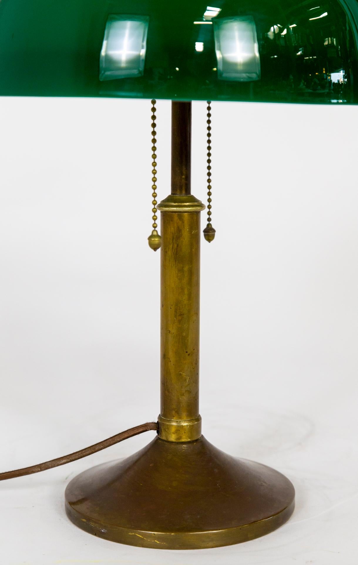 A 2-light desk lamp with acorn pull string switches, a green glass shade (white interior), and a brass finial mimicking the semi-sphere shade shape; with a simple, weighted brass base. From the early 1920s. 2 medium based sockets. Newly wired.