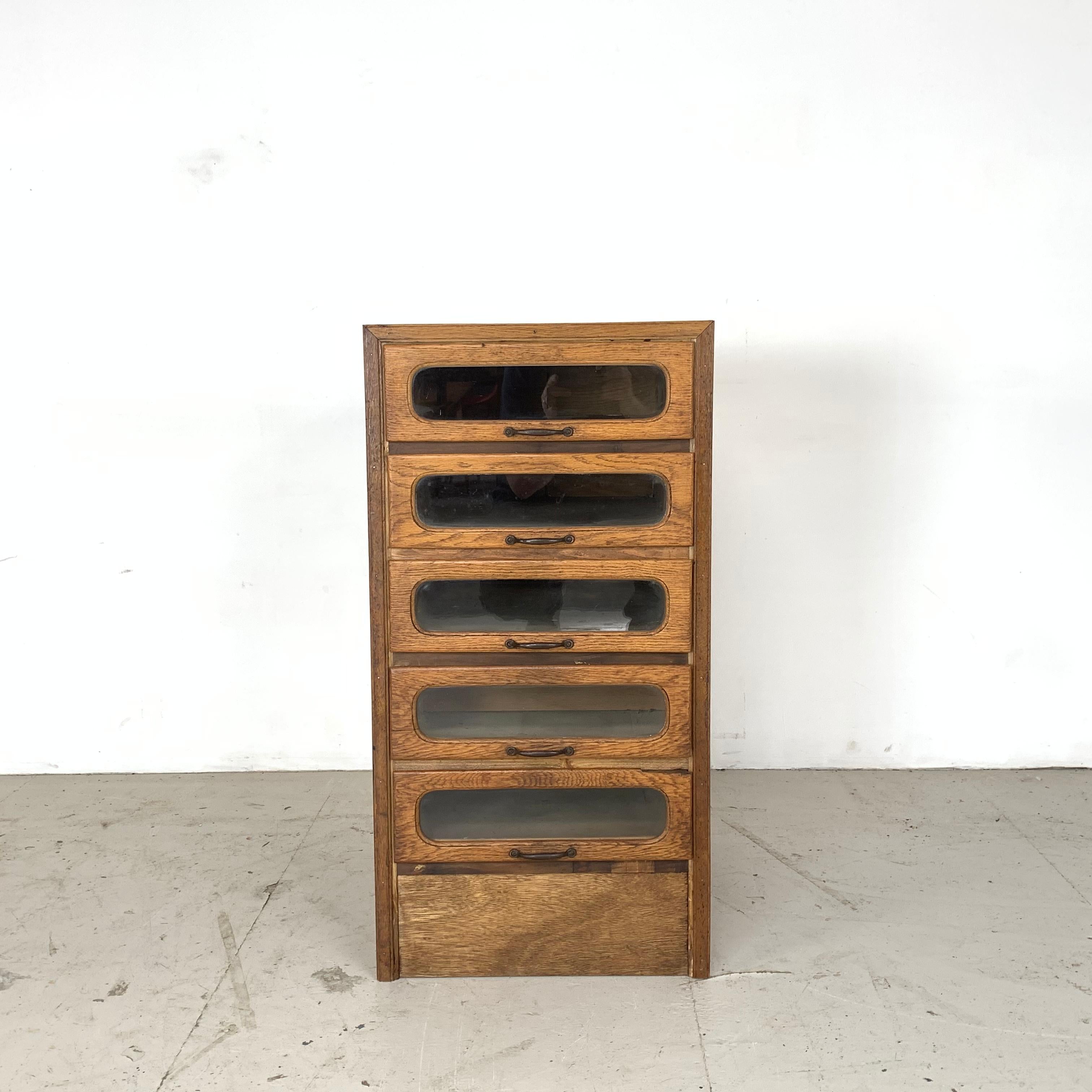 5 drawer single column haberdashery shop cabinet. 

It has 5 glass fronted drawers, all with original wooden handles.

Approximate dimensions:

Height 84 cm

Width 43 cm

Depth 54 cm

Drawers 34.5 cm x 48 cm x 10 cm.

Overall in good